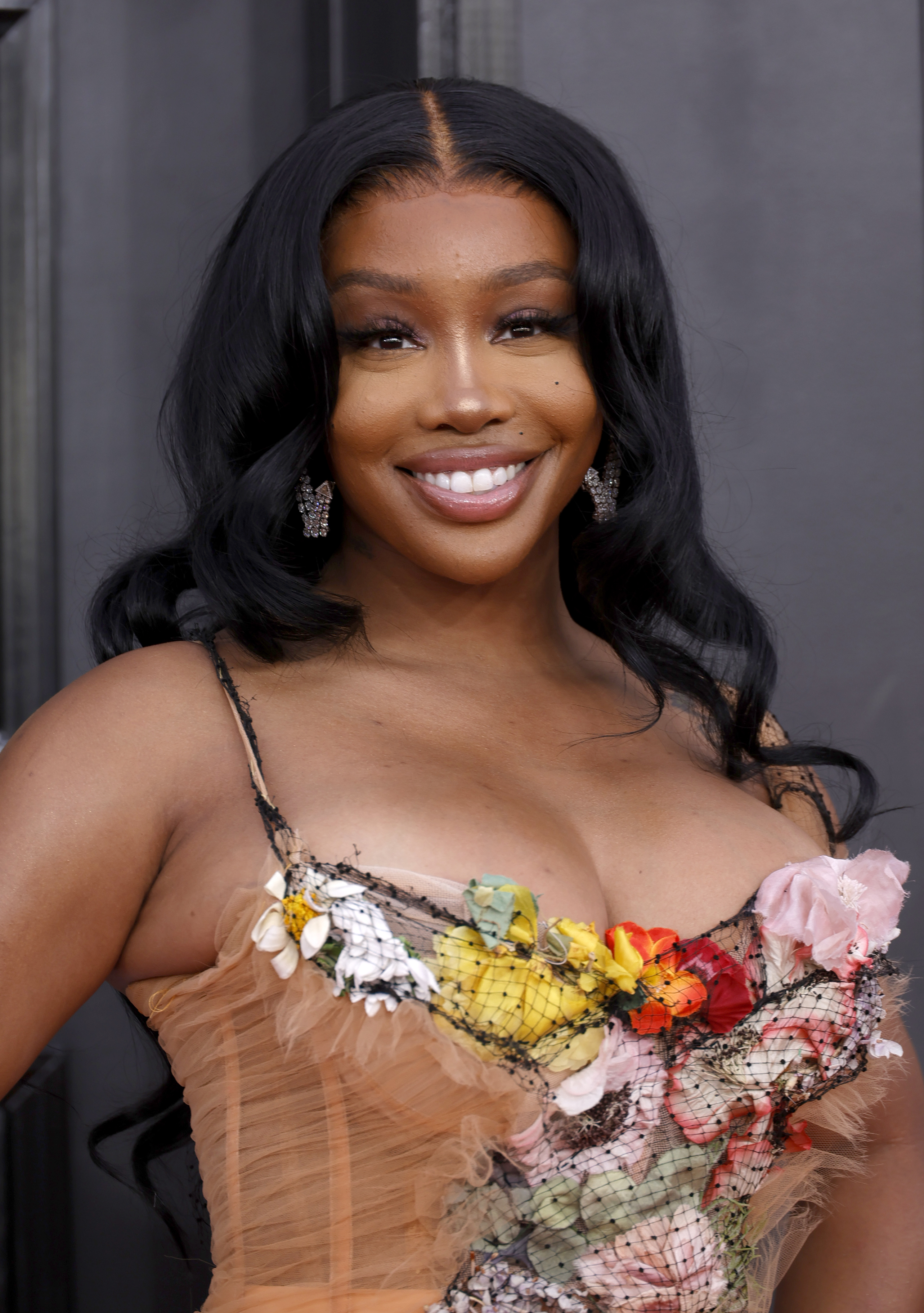 Close-up of SZA smiling and wearing a colorful, spaghetti-strap top