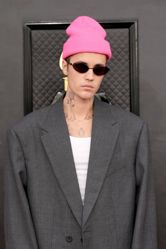 Close-up of Justin at a media event in an oversize jacket, sunglasses, and a beanie