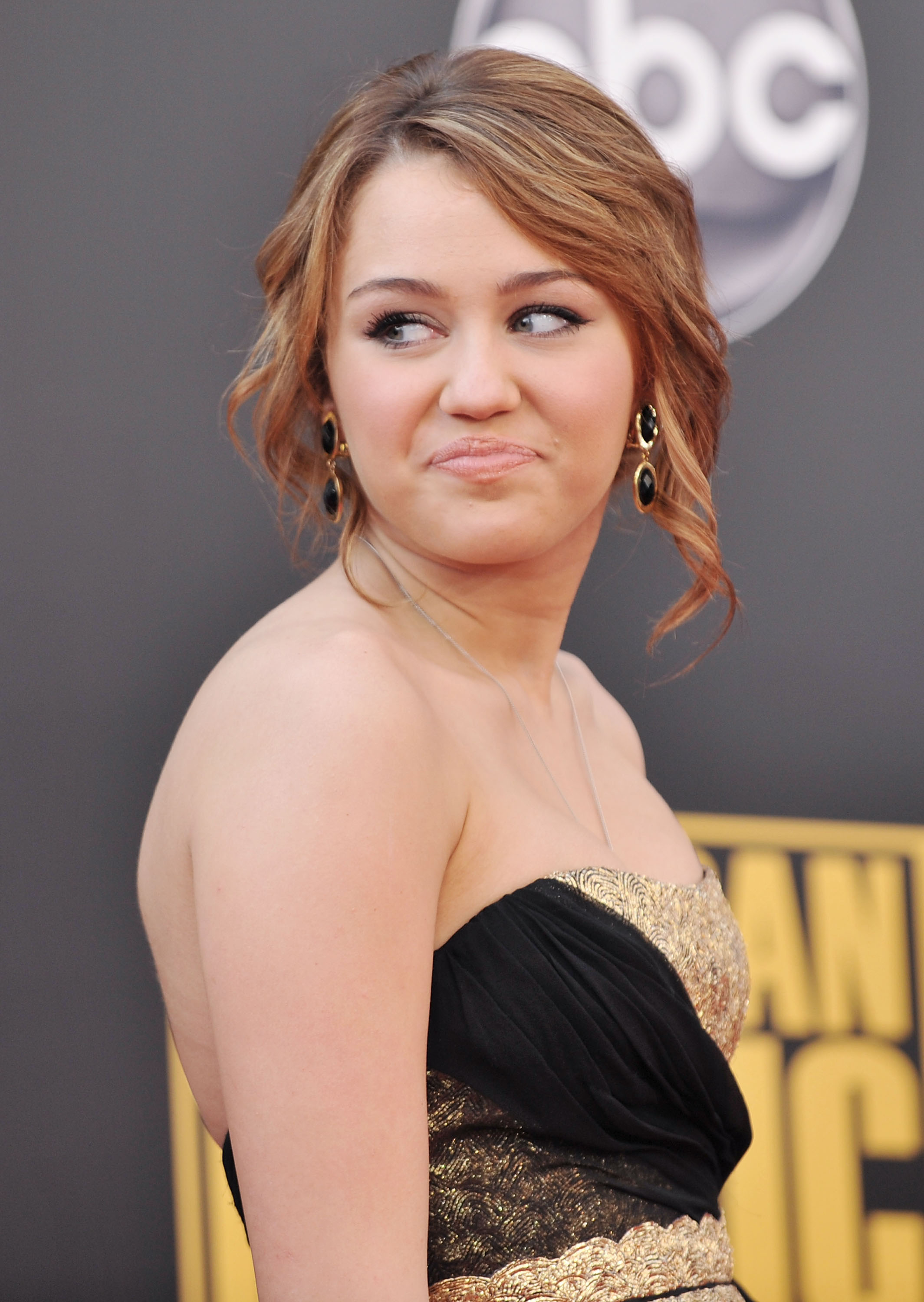 Close-up of Miley at a media event in a strapless outfit