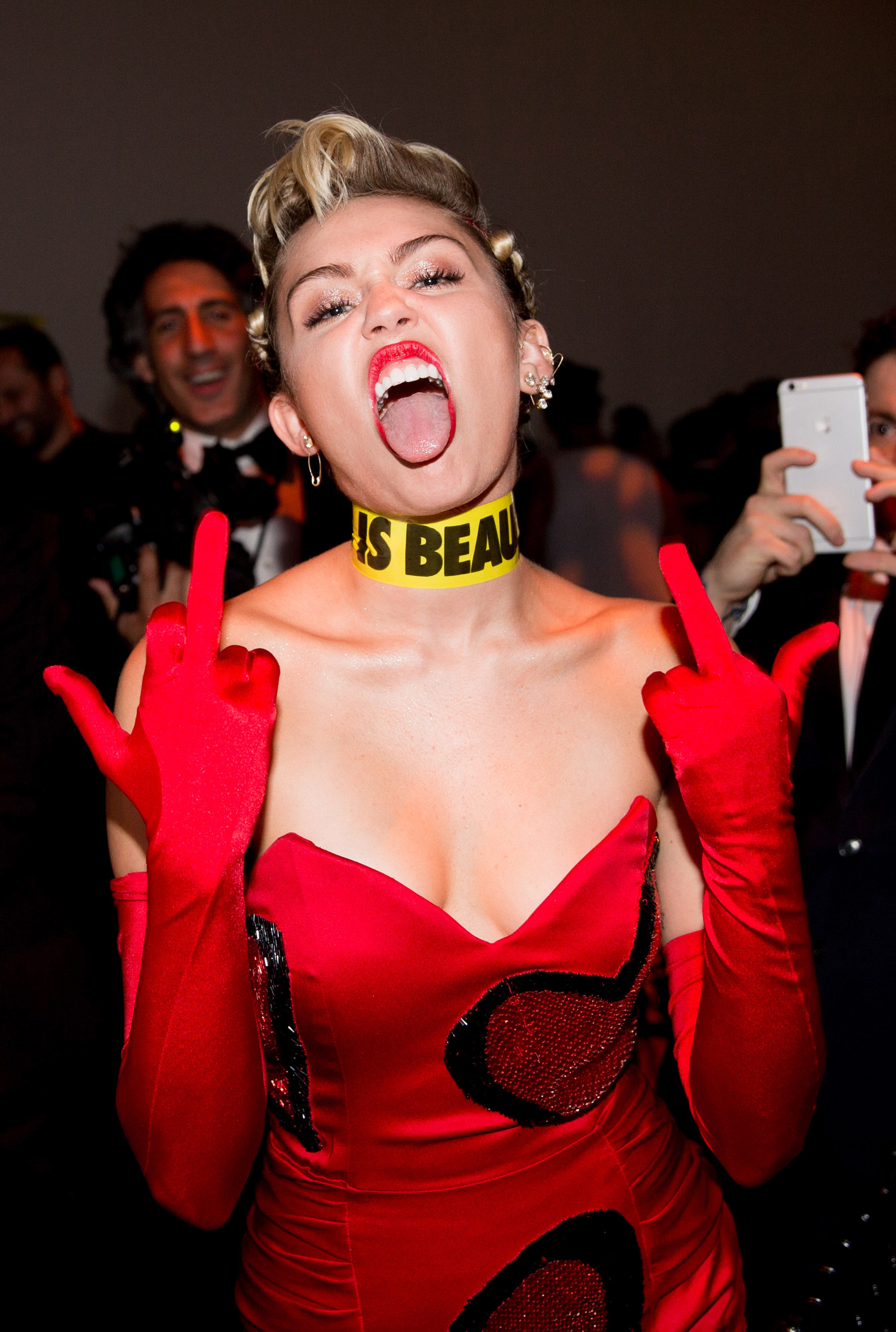 Close-up of Miley sticking her tongue out and raising her middle fingers