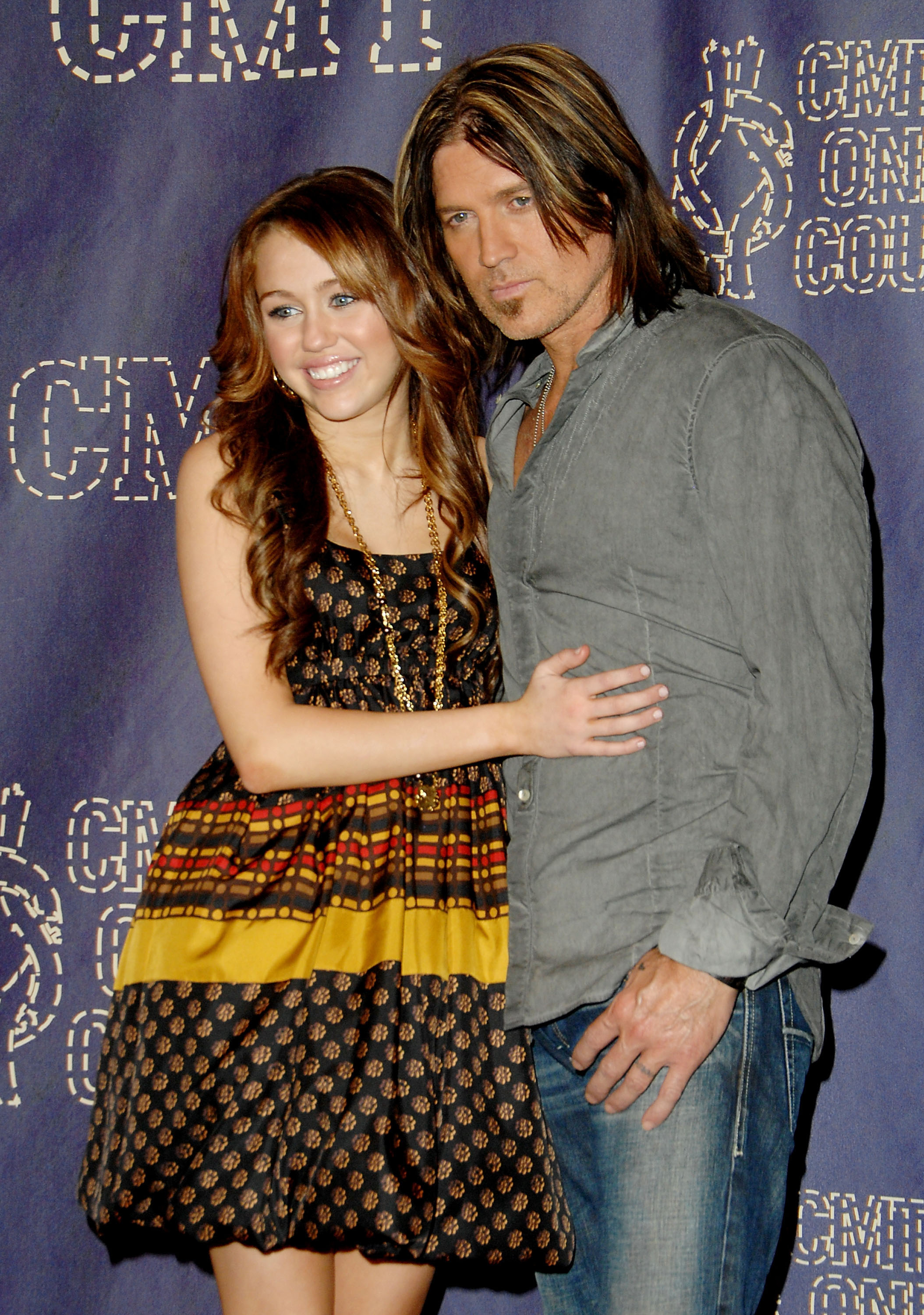 Close-up of Miley and Billy Ray smiling at a media event