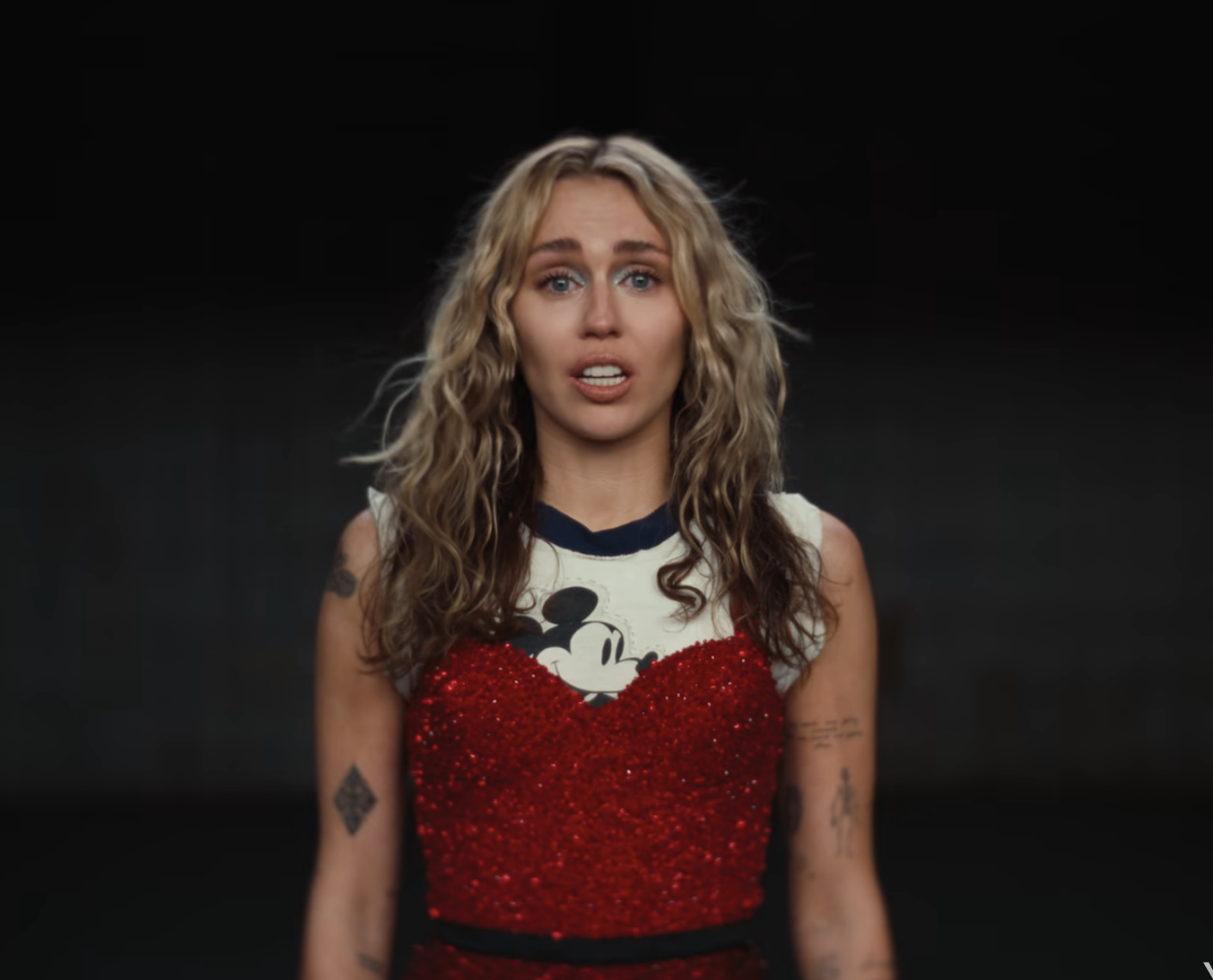 Close-up of Miley from the video, in a sparkly outfit and Mickey Mouse T-shirt