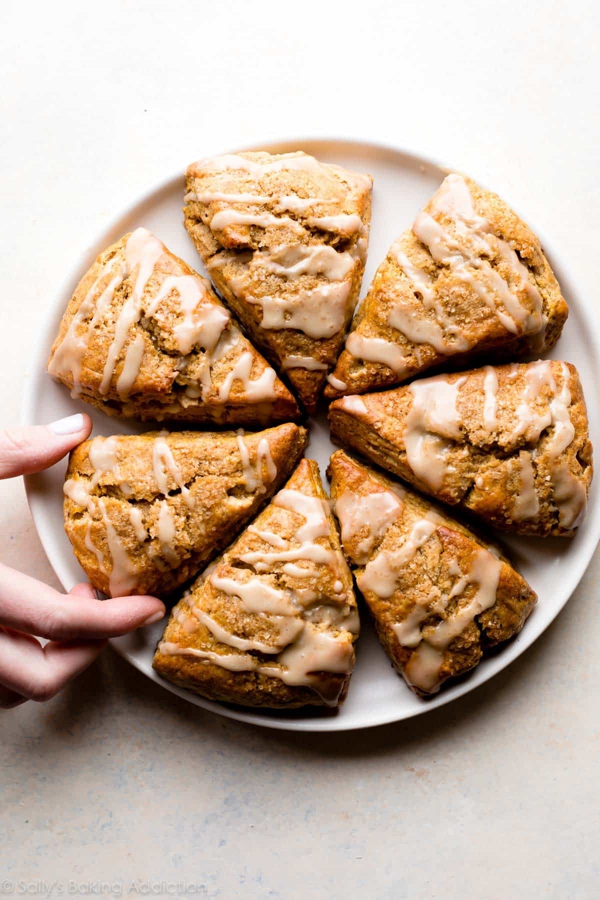 someone reaching for pumpkin scones on a plate