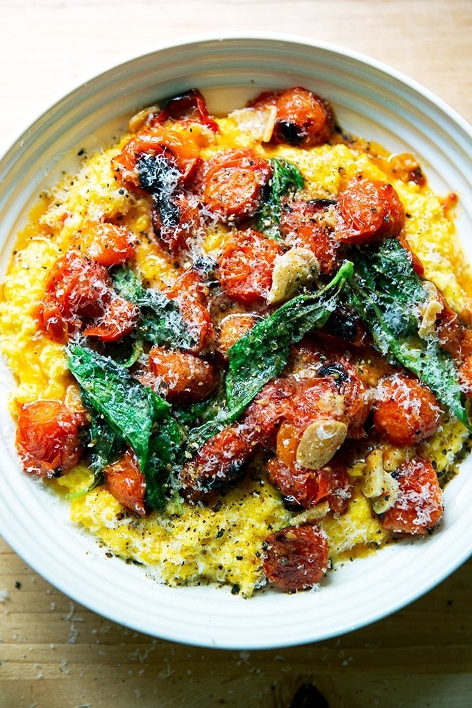 corn polenta in a bowl topped with tomatoes and basil