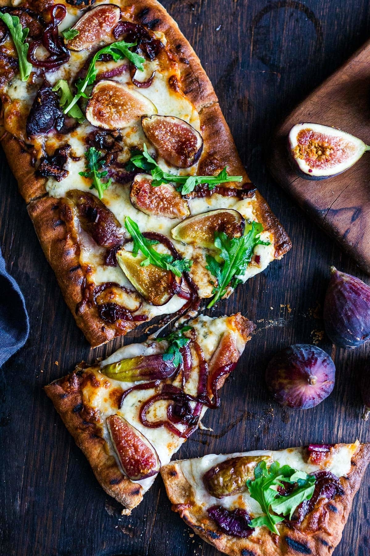 a sliced fig pizza topped with arugula