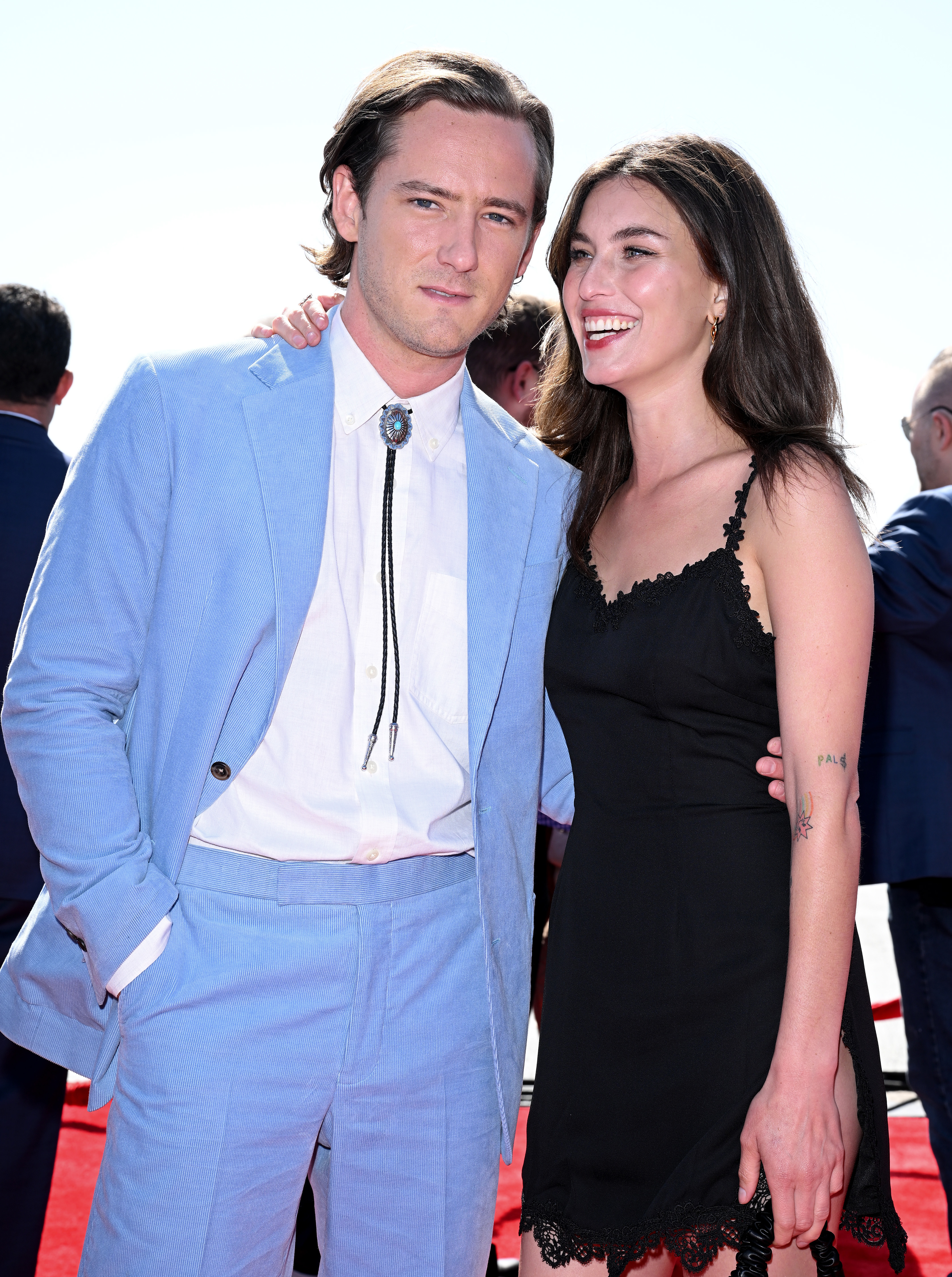 Lewis Pullman and Rainey Qualley smiling on the red carpet