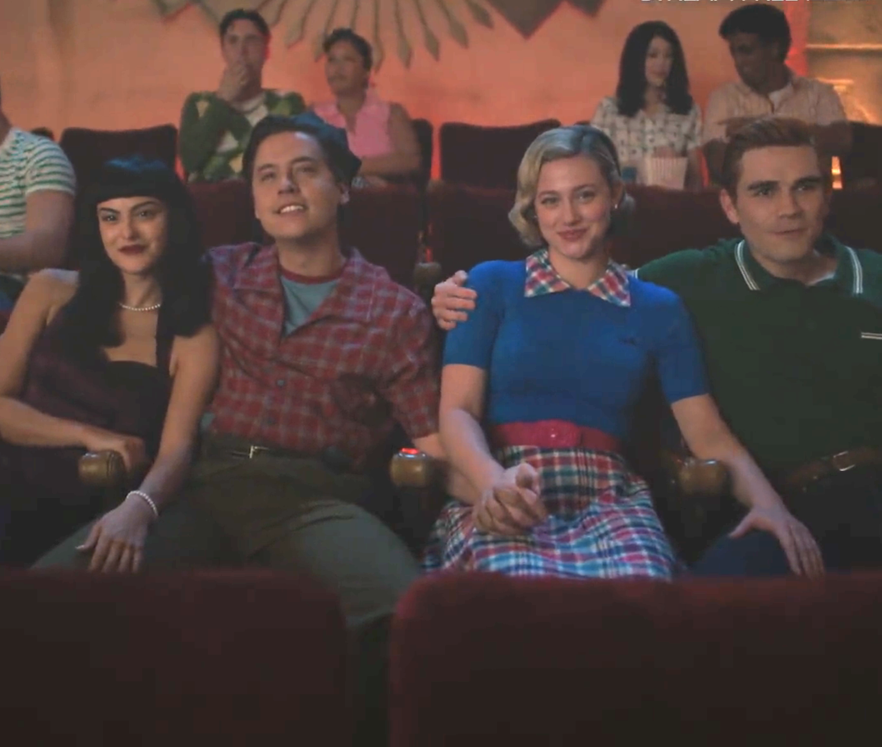 Closeup of Veronica, Jughead, Betty, and Archie sitting and all holding hands