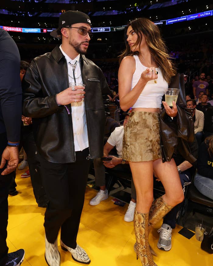Closeup of Bad Bunny and Kendall Jenner holding drinks at a sports event