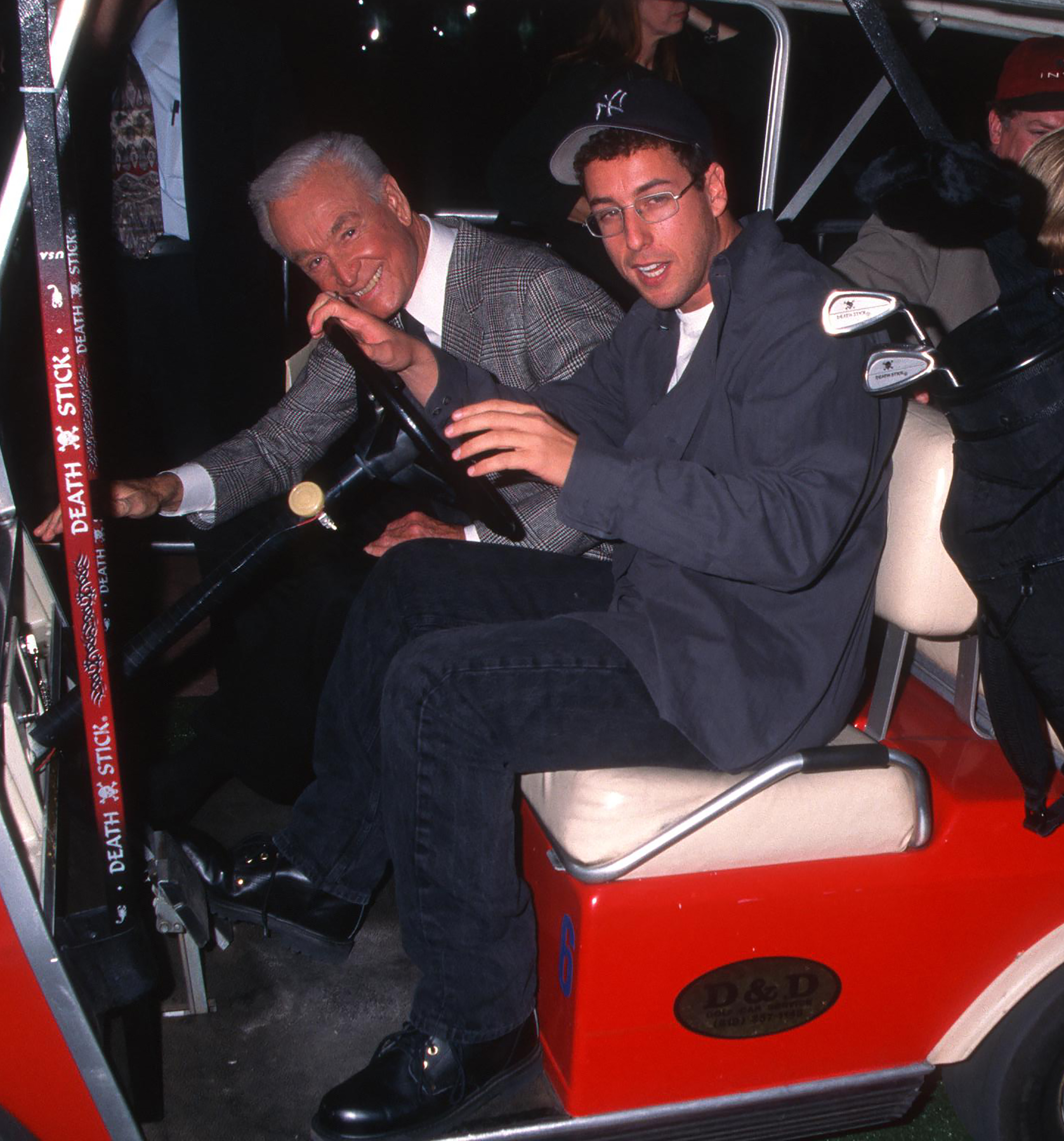 Closeup of Bob Barker and Adam Sandler in a golf cart
