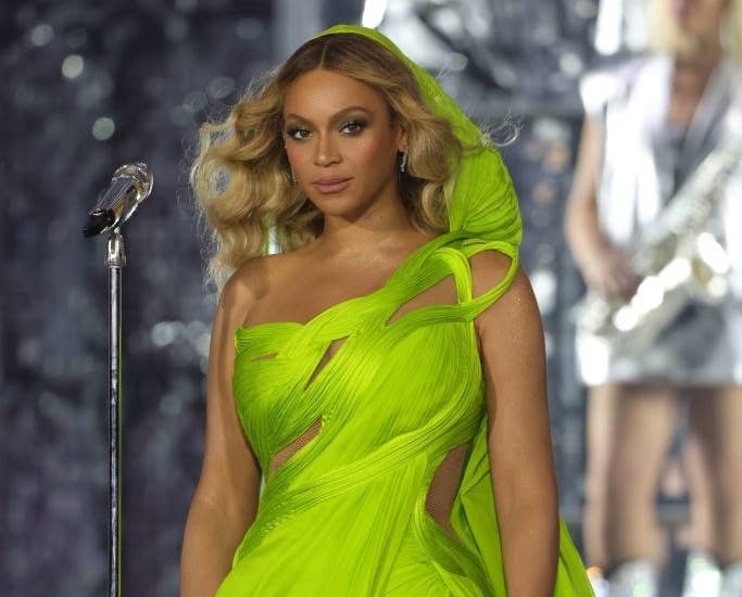 Closeup of Beyoncé on stage wearing a one-shouldered gown that mimics waves
