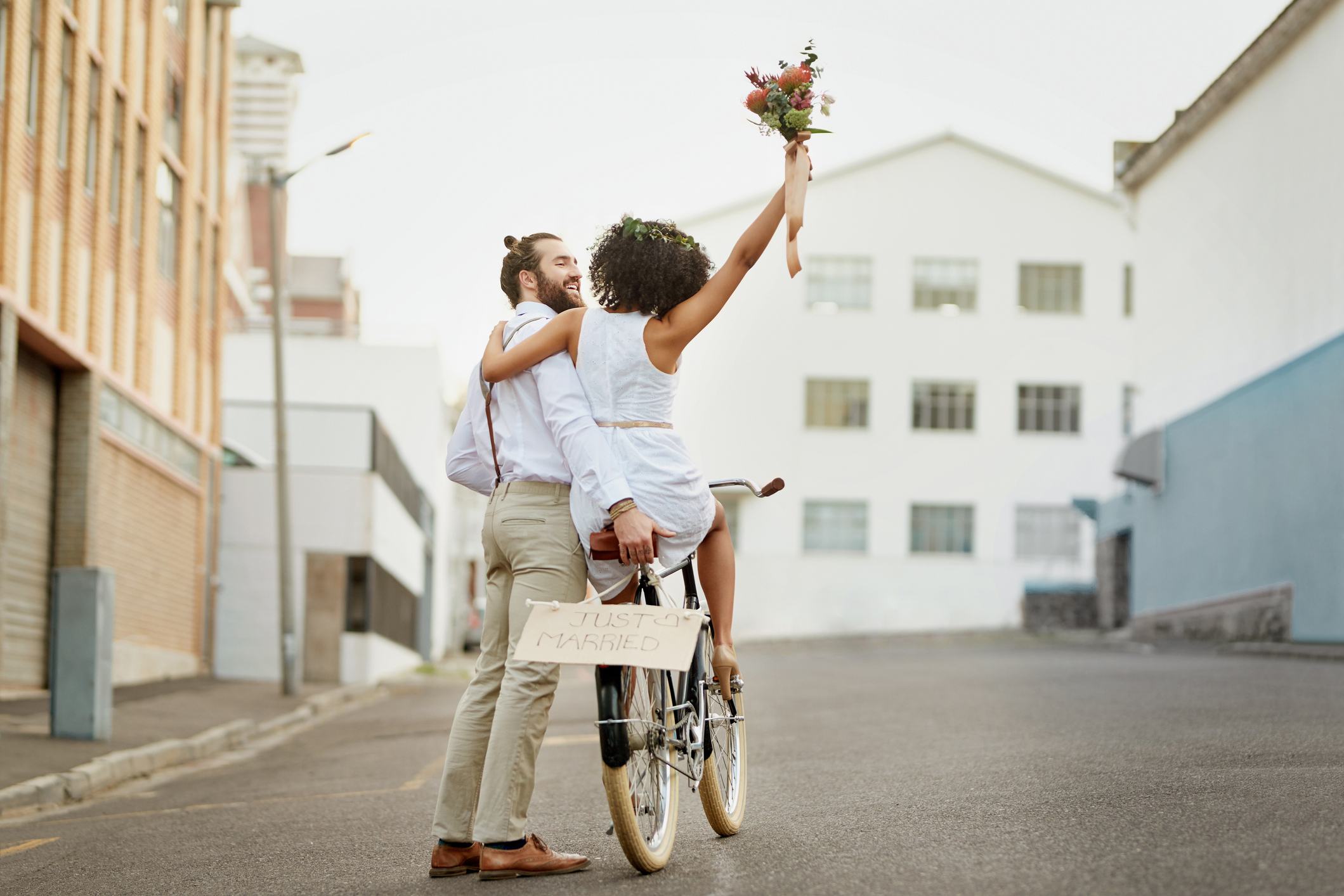 A happy couple embracing as the woman holds up a bouquet