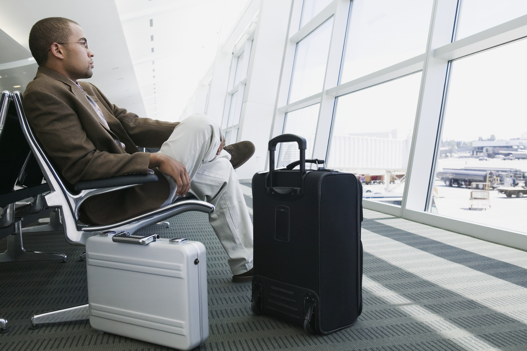 A man sits in an airport with luggage