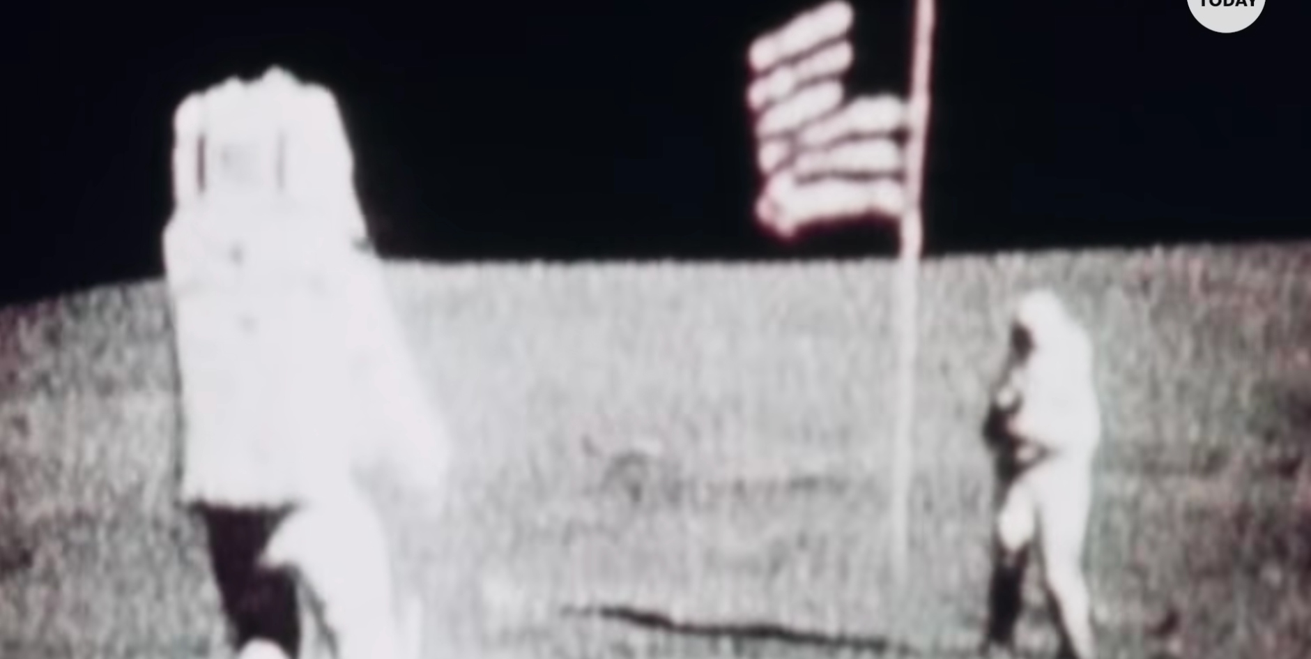 Two astronauts from the Apollo 11 moon landing are standing by the American flag