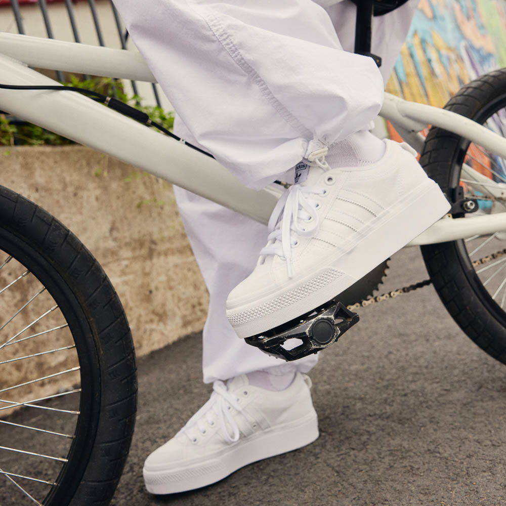 model riding bike in white platform tennis shoes