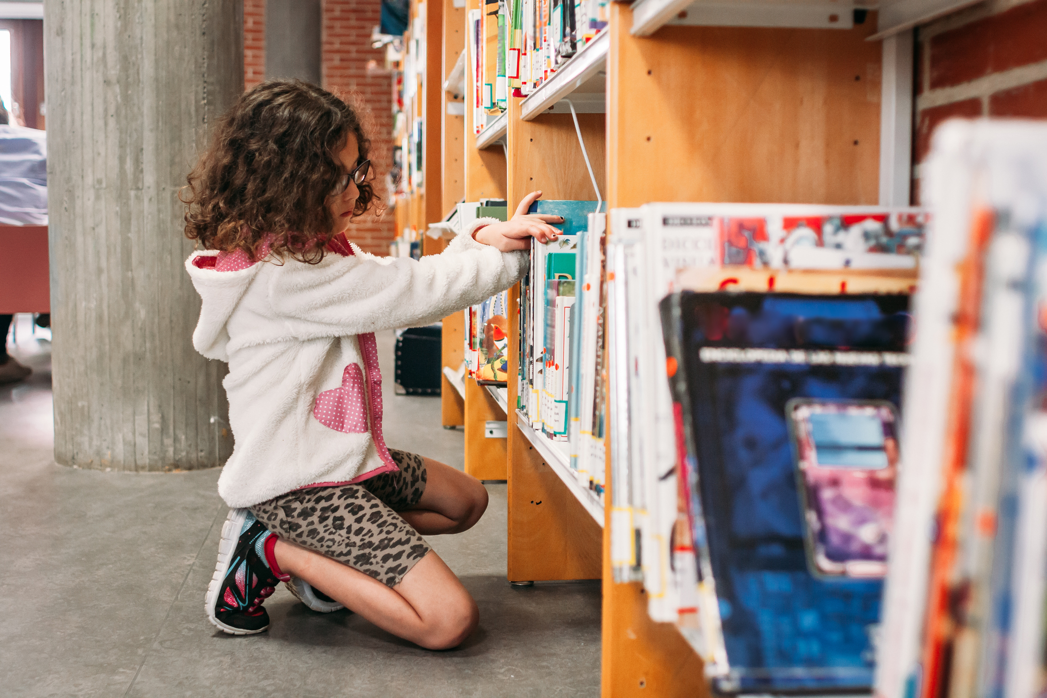 A little girl is browsing for books at the library