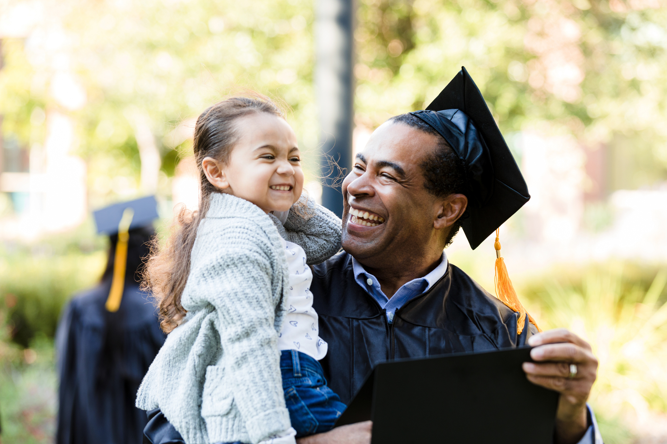 A newly-graduated father is carrying his daughter