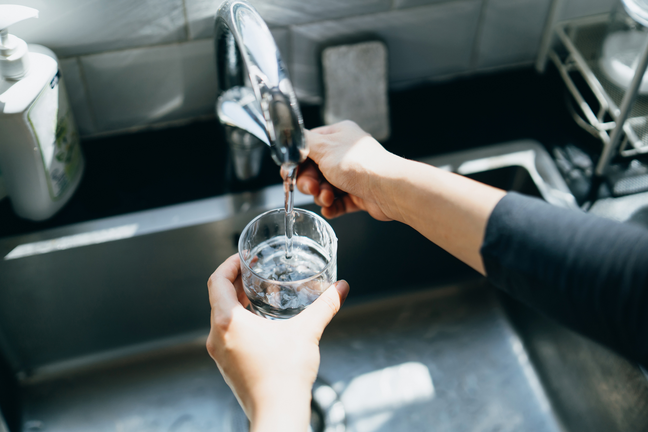 A person pouring a glass of water