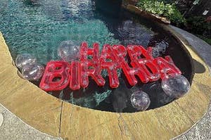 red inflatable "happy birthday" sign in a pool