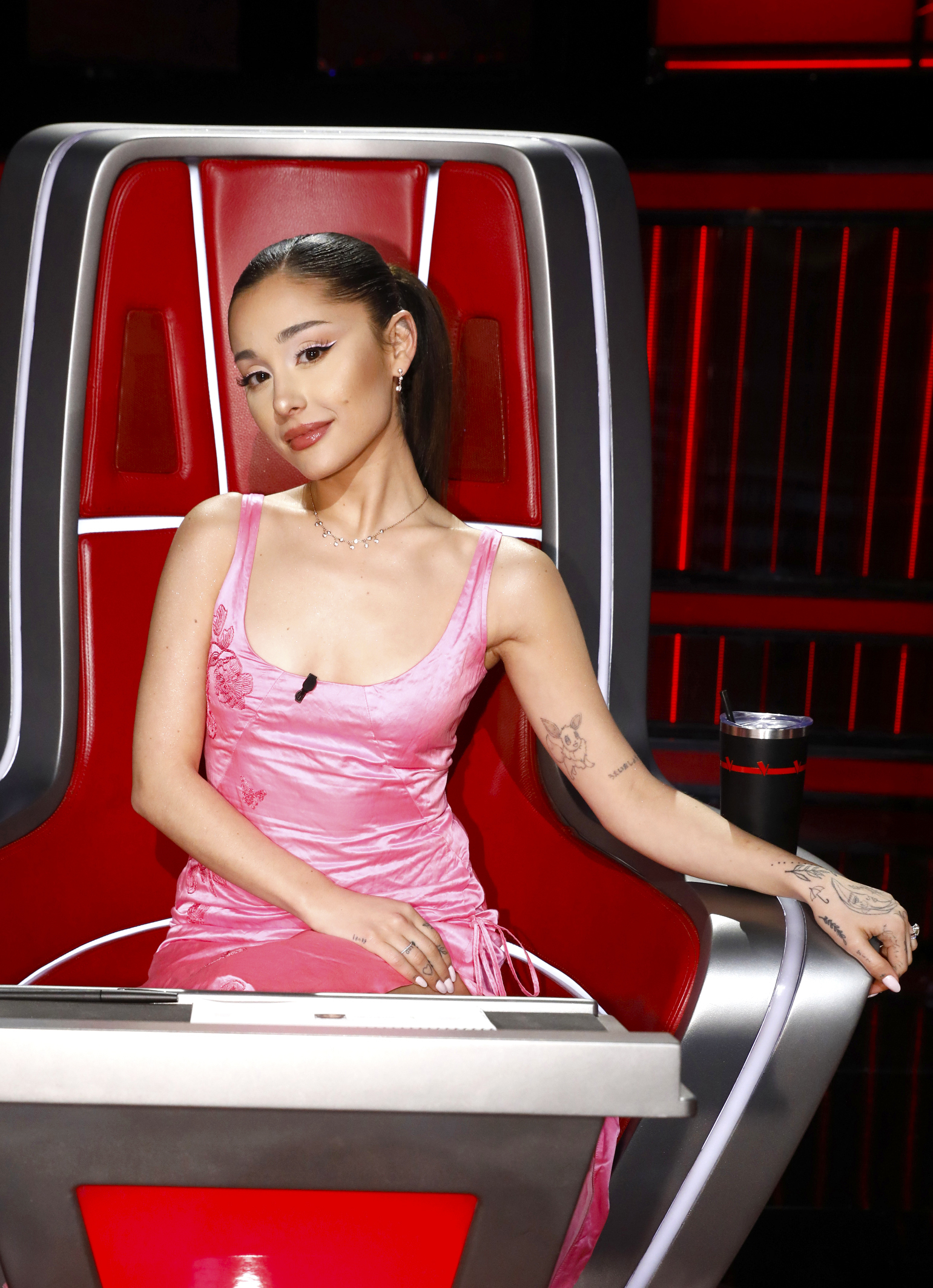Ariana sitting in the judge&#x27;s chair on the set of the voice