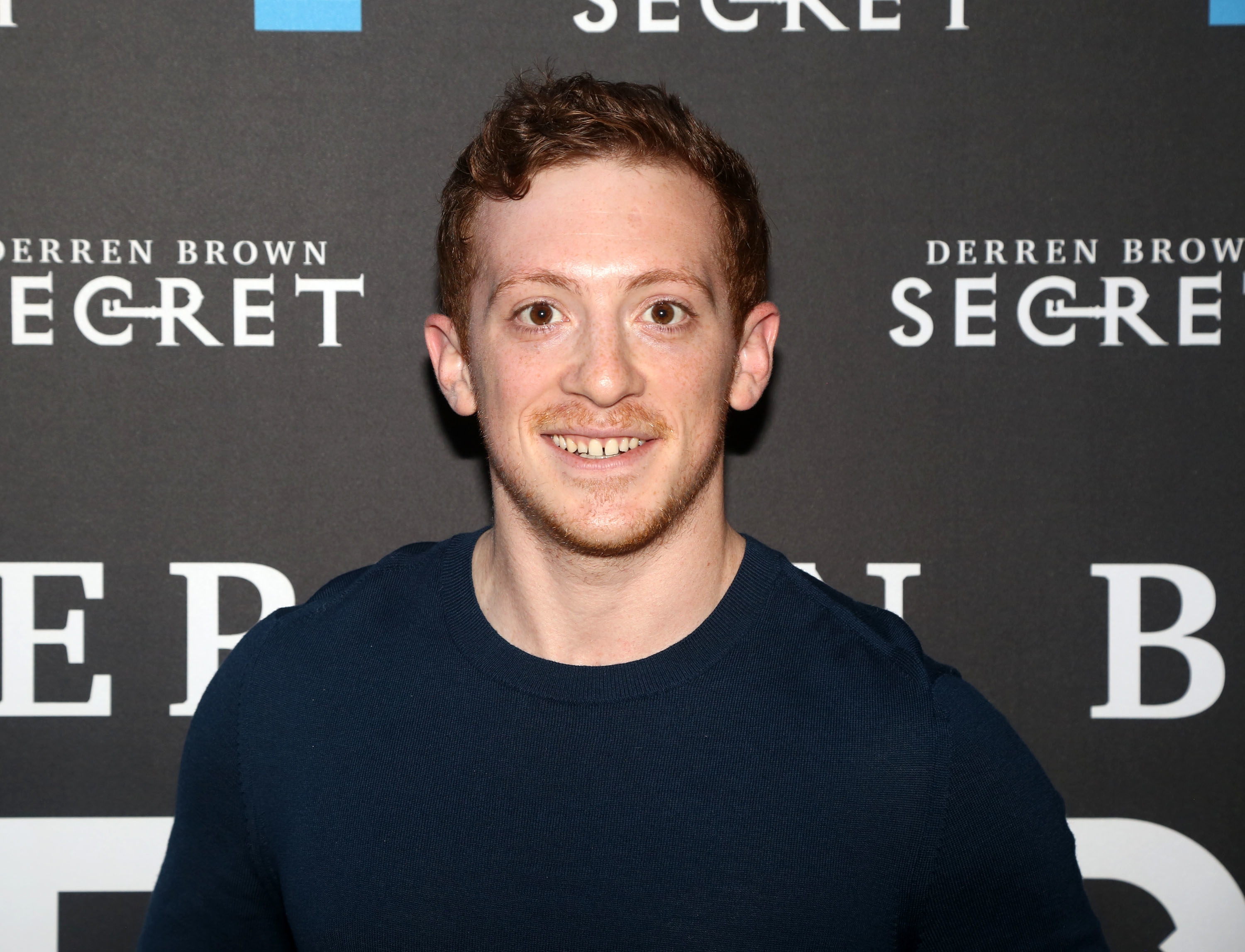 A closeup of Ethan Slater smiling at a media event