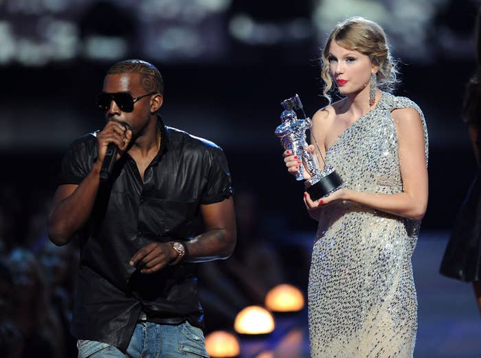 Taylor Swift standing on stage holding her award as Kanye interrupts her