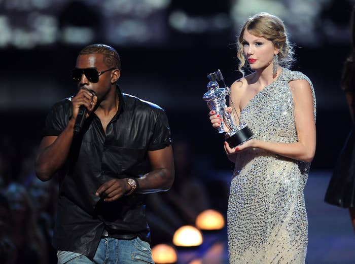 Taylor Swift standing on stage holding her award as Kanye interrupts her