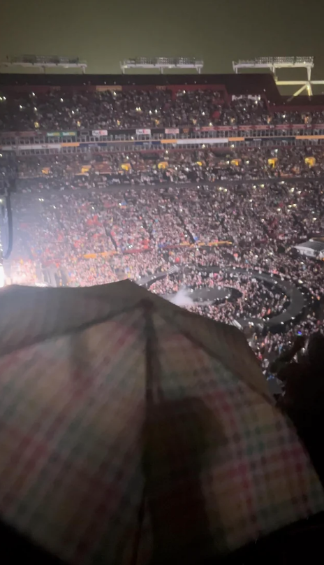 An umbrella blocking bystanders view of a concert