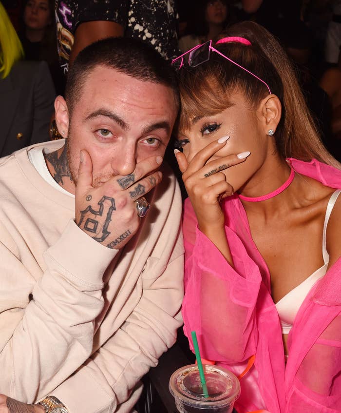 Closeup of Mac Miller and Ariana Grande making a silly pose by hiding behind their hands