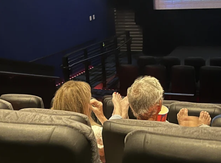 People with their bare feet on the seat in a theater