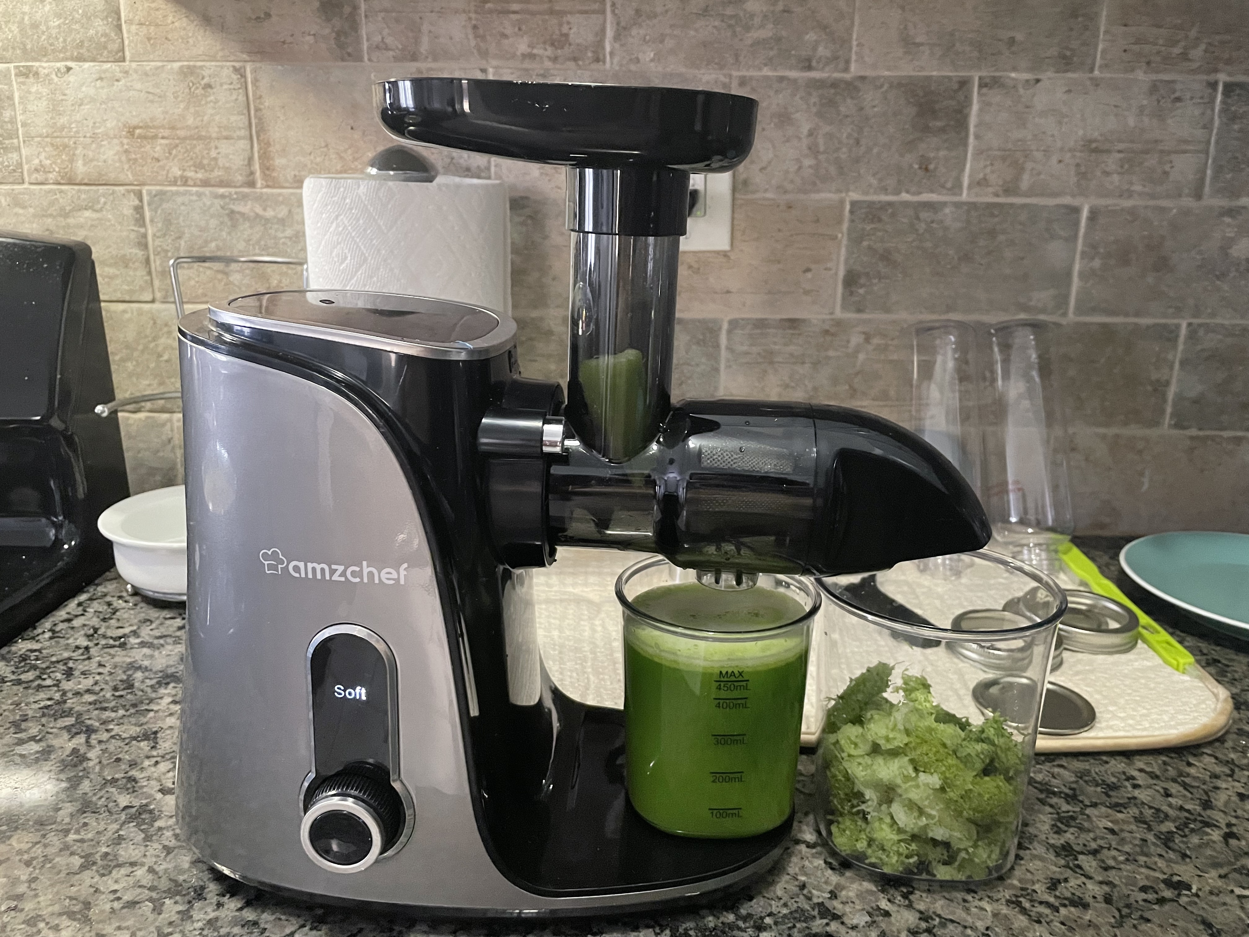 reviewer&#x27;s gray juicer with a fresh cup of green juice