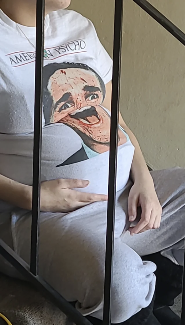 Woman wearing an &quot;American Psycho&quot; T-shirt showing his open mouth stretched over the bump