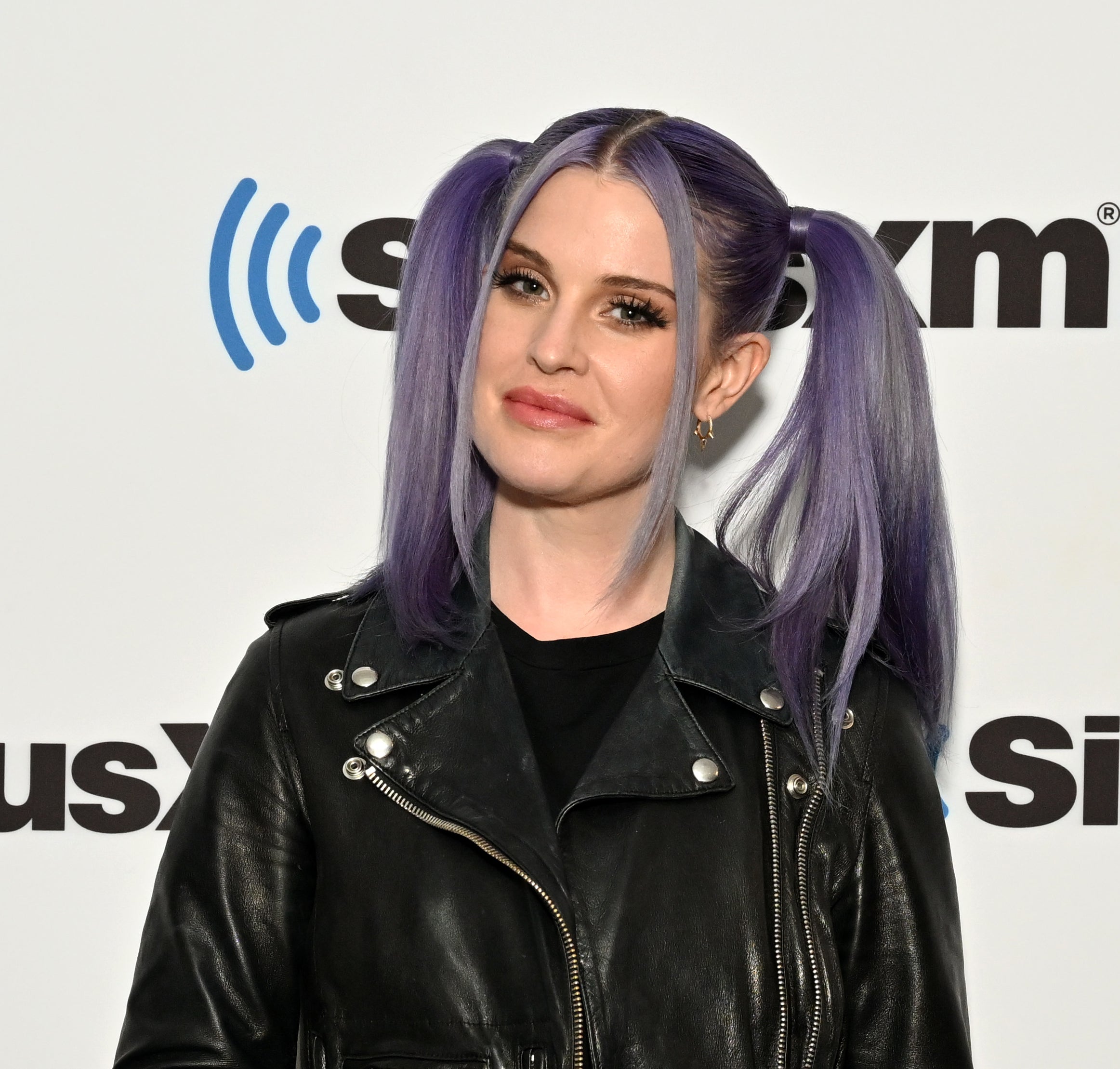 Close-up of Kelly at a media event in pigtails and a leather jacket