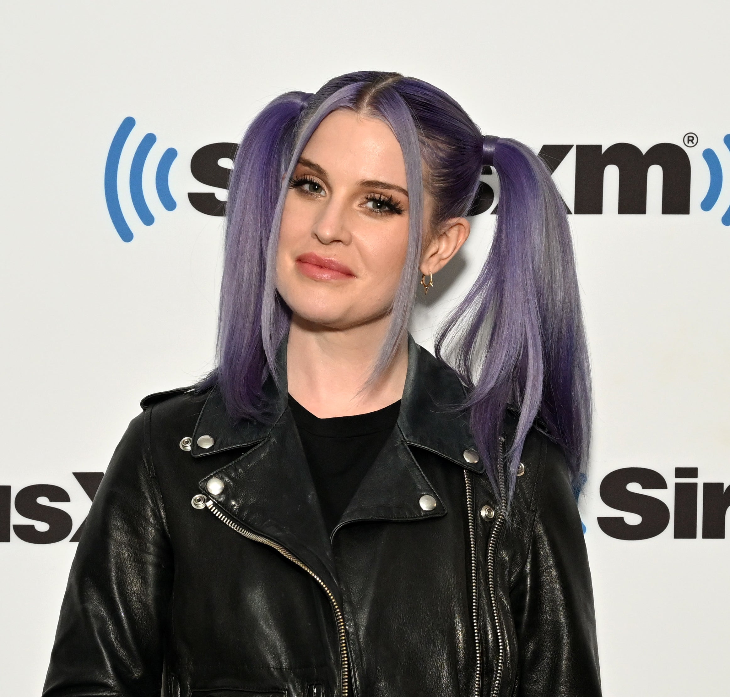 Close-up of Kelly at a media event in pigtails and a leather jacket