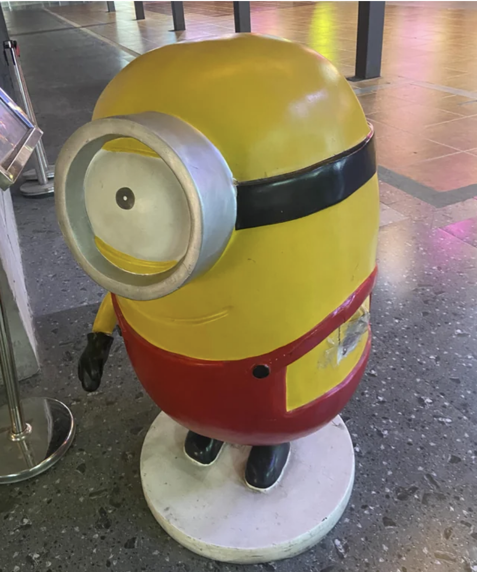 A Minion statue from the move &quot;The Minions&quot; with a pained smile and a missing arm