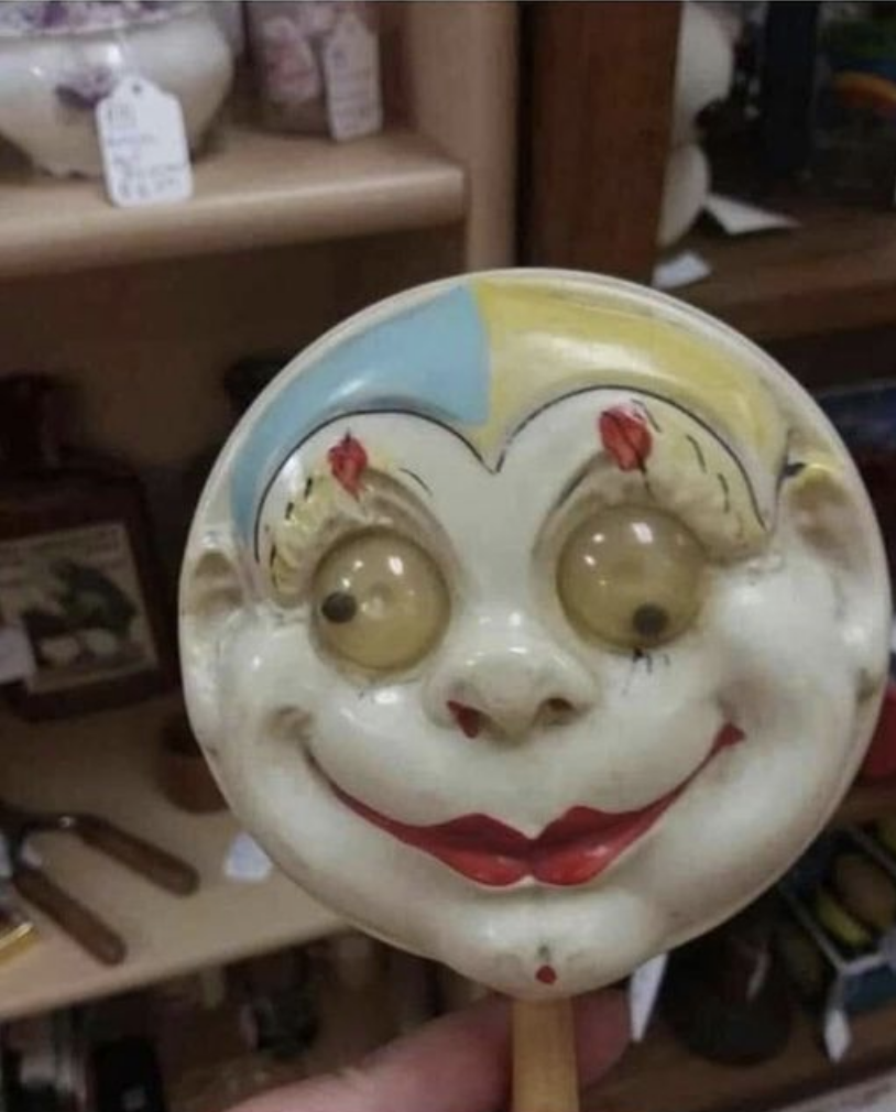 Close-up of a very terrifying circular baby rattle with eyes going two different ways, a painted-on bright red lipstick, and a nosebleed
