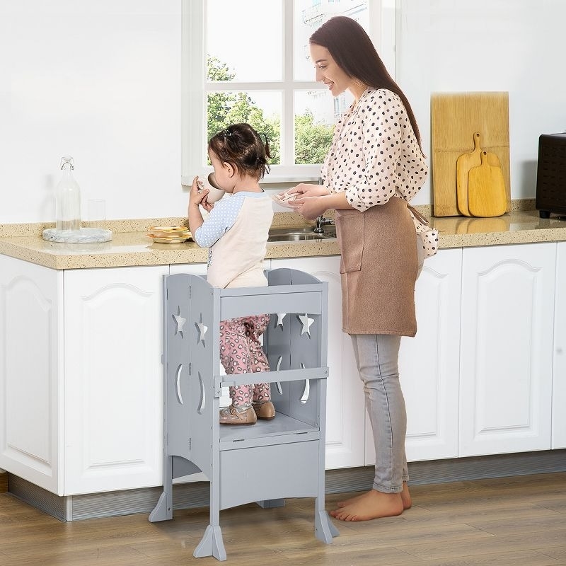 Child model stands on a stool while an adult model watches