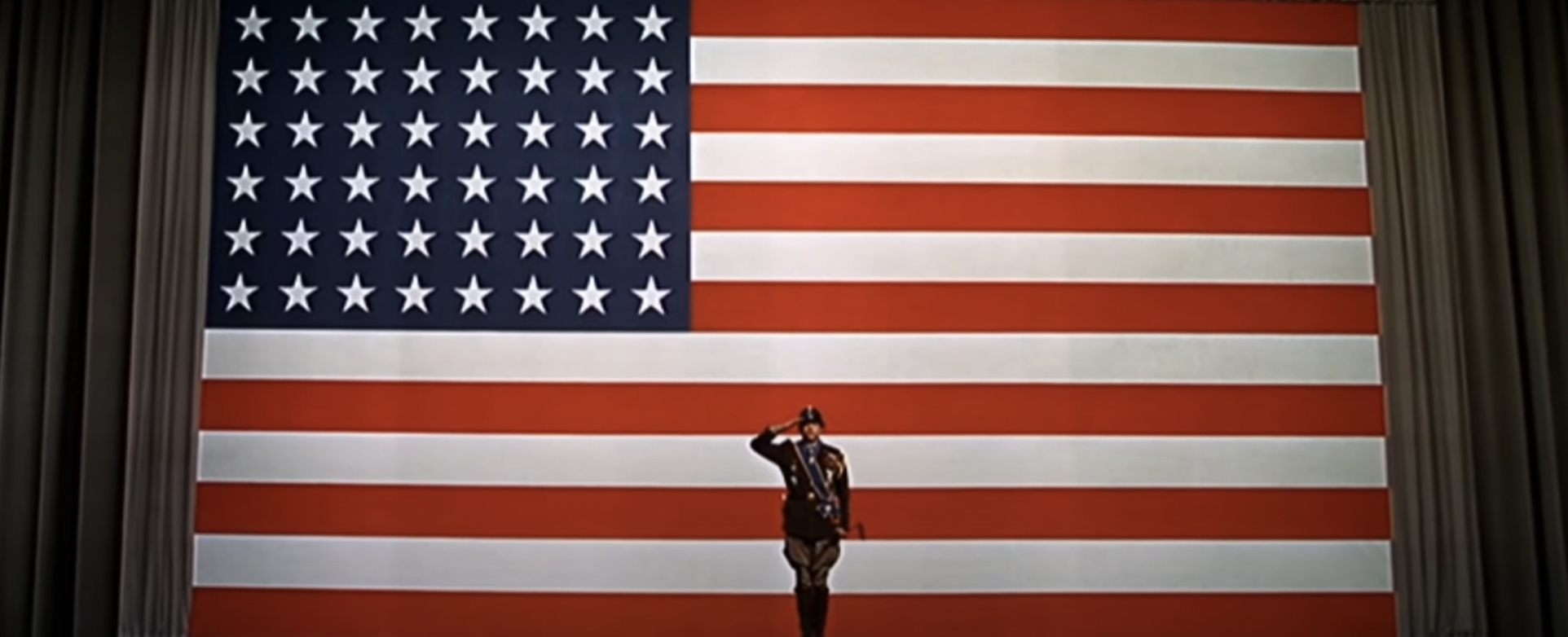 a man salutes in front of the US flag