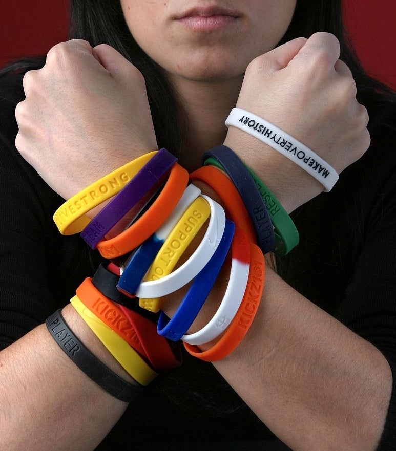 person&#x27;s arms covered in plastic bracelets