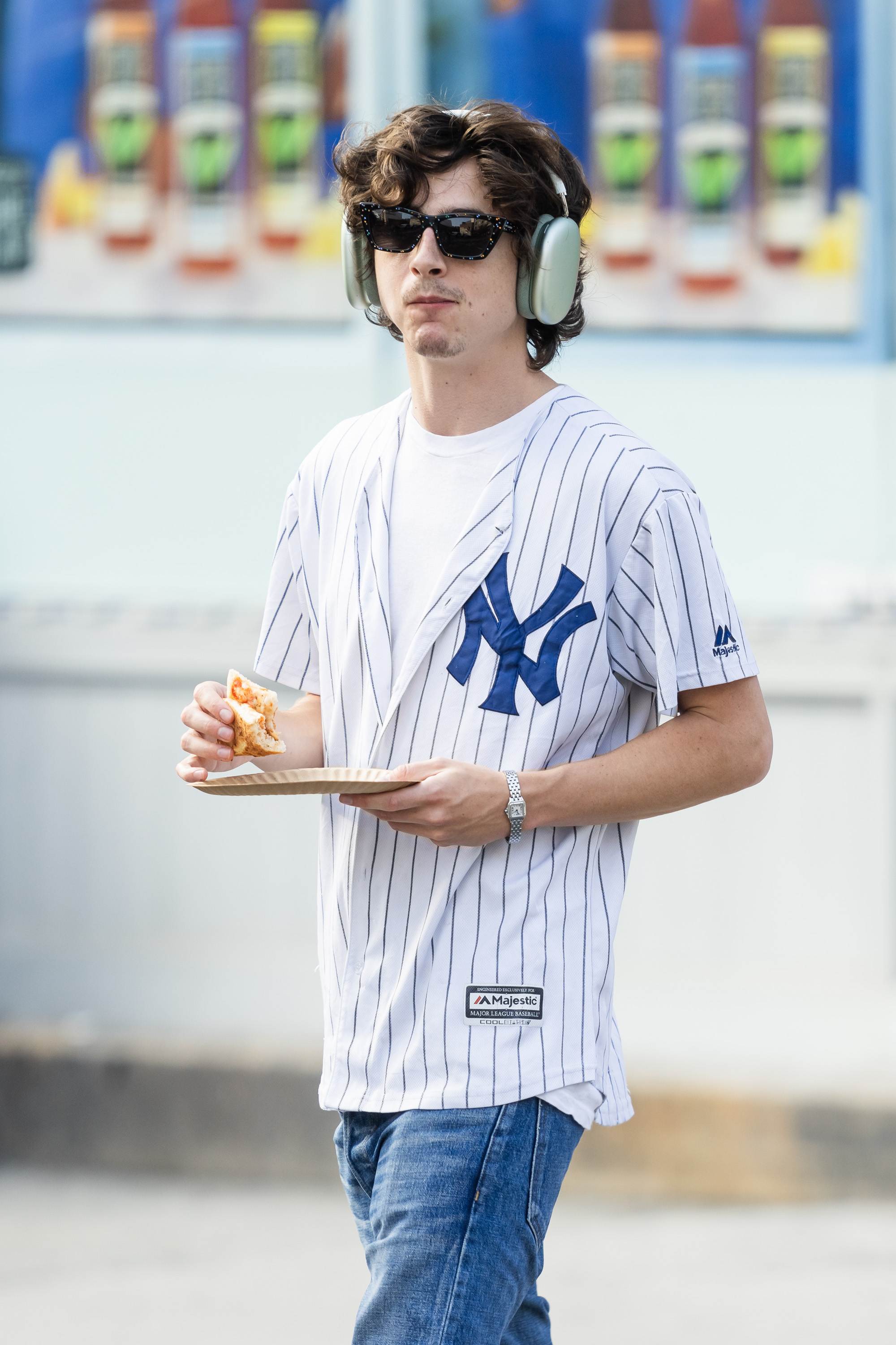 Timothee walking around eating a slice of pizza