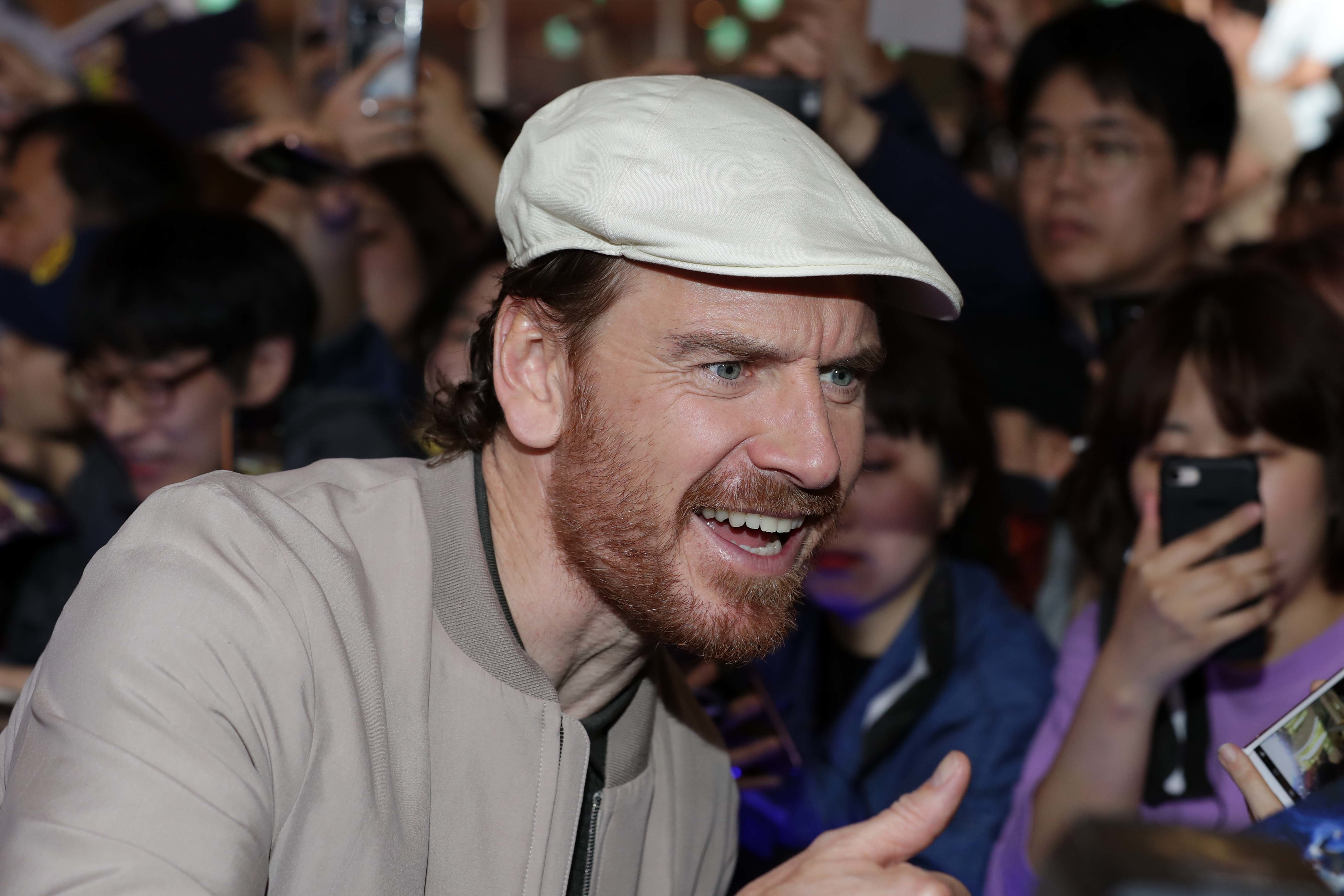 Close-up of Michael wearing a cap at a public event and giving the thumbs-up