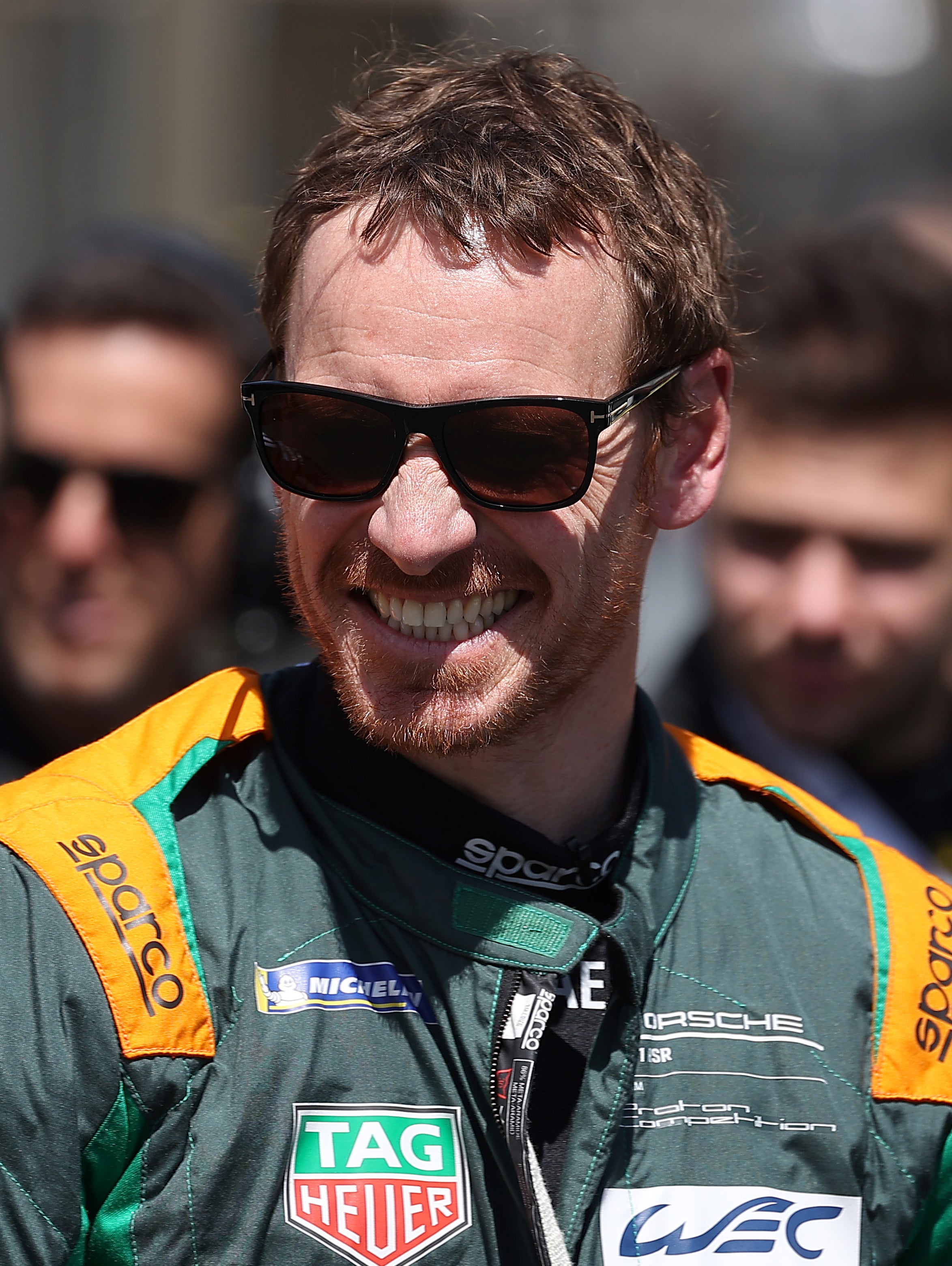 Close-up of Michael smiling and wearing a uniform as a race car driver