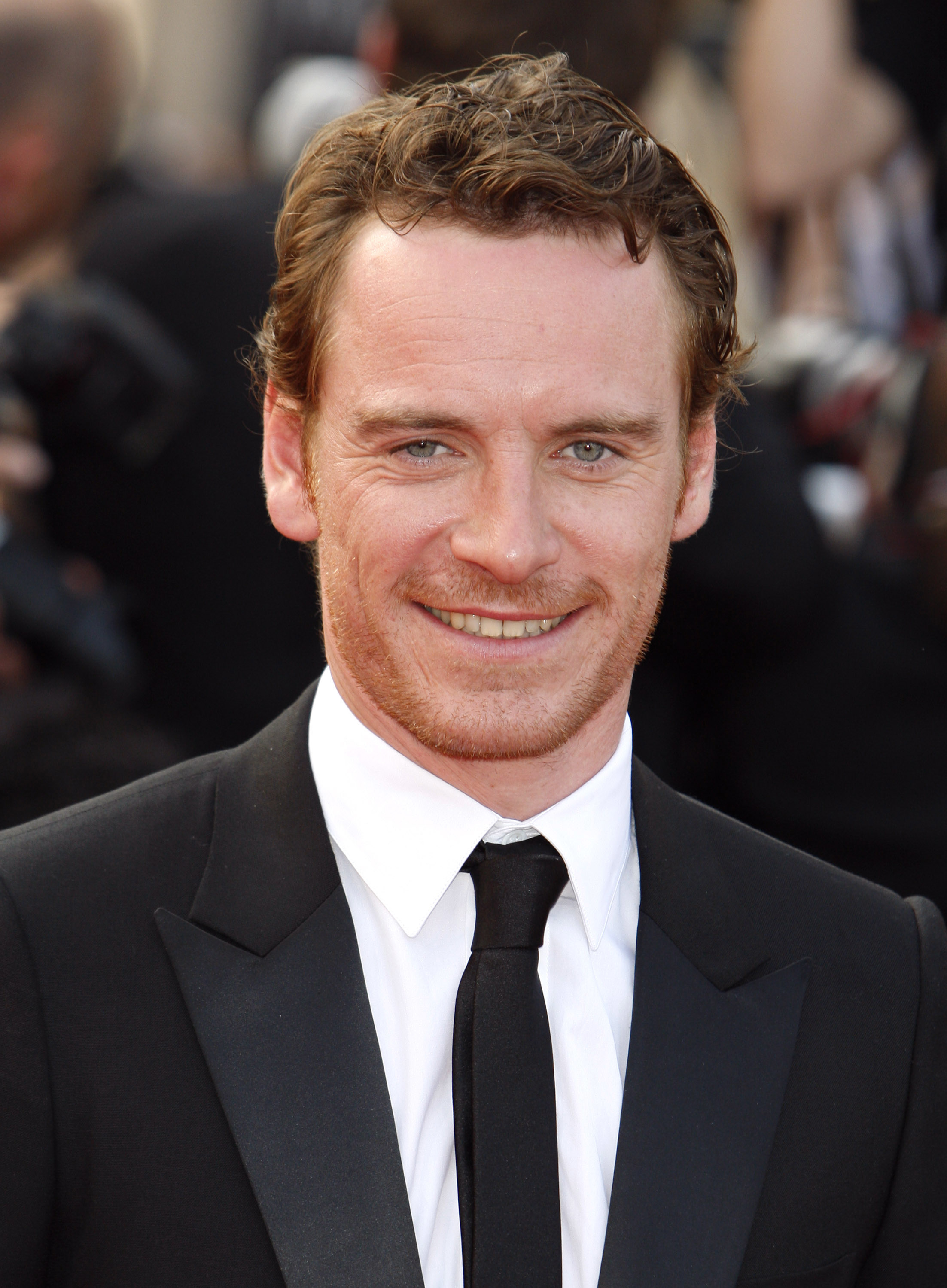 Close-up of Michael smiling in a suit and tie at a media event