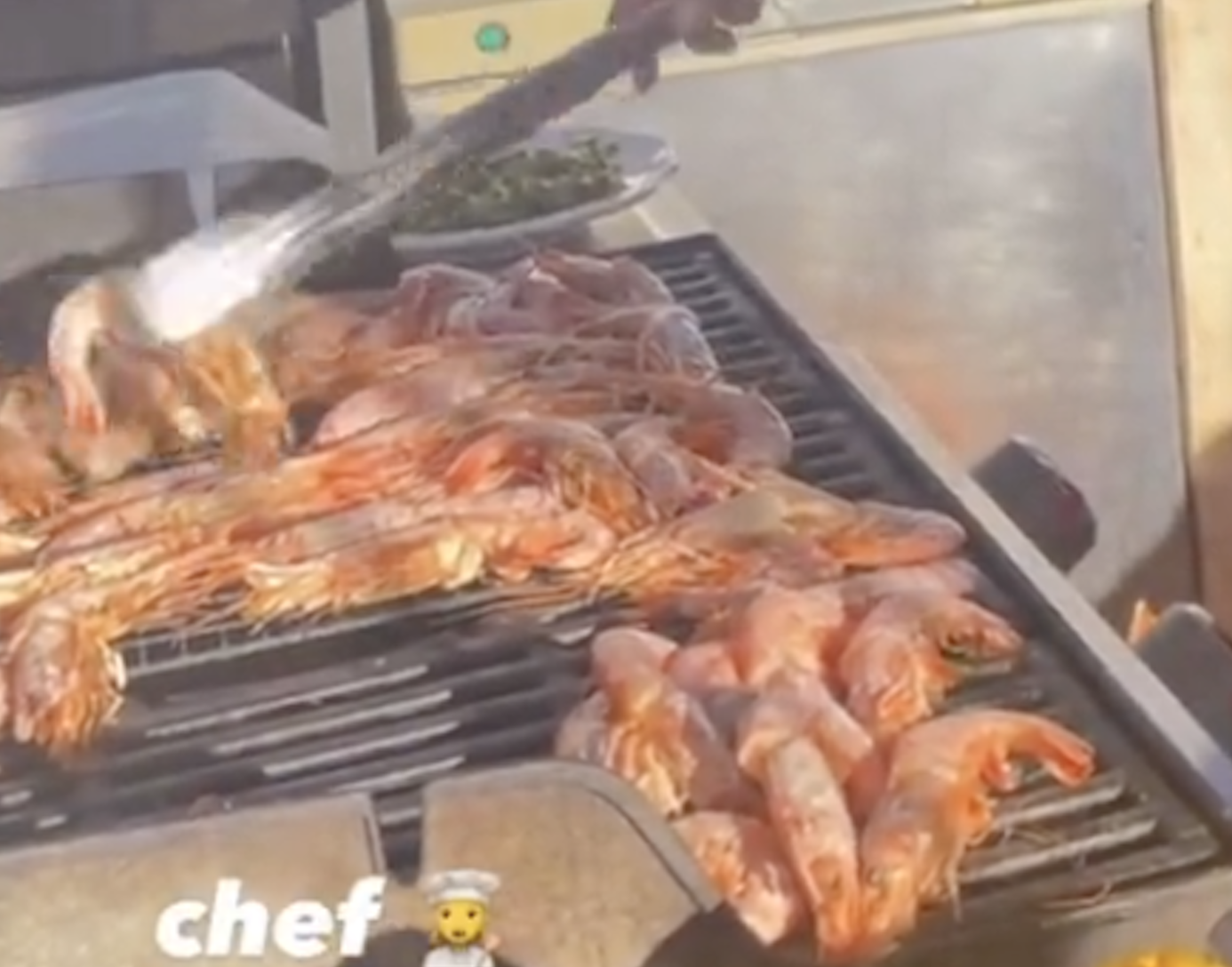 a zoomed in angle of dua lipa grilling shrimp