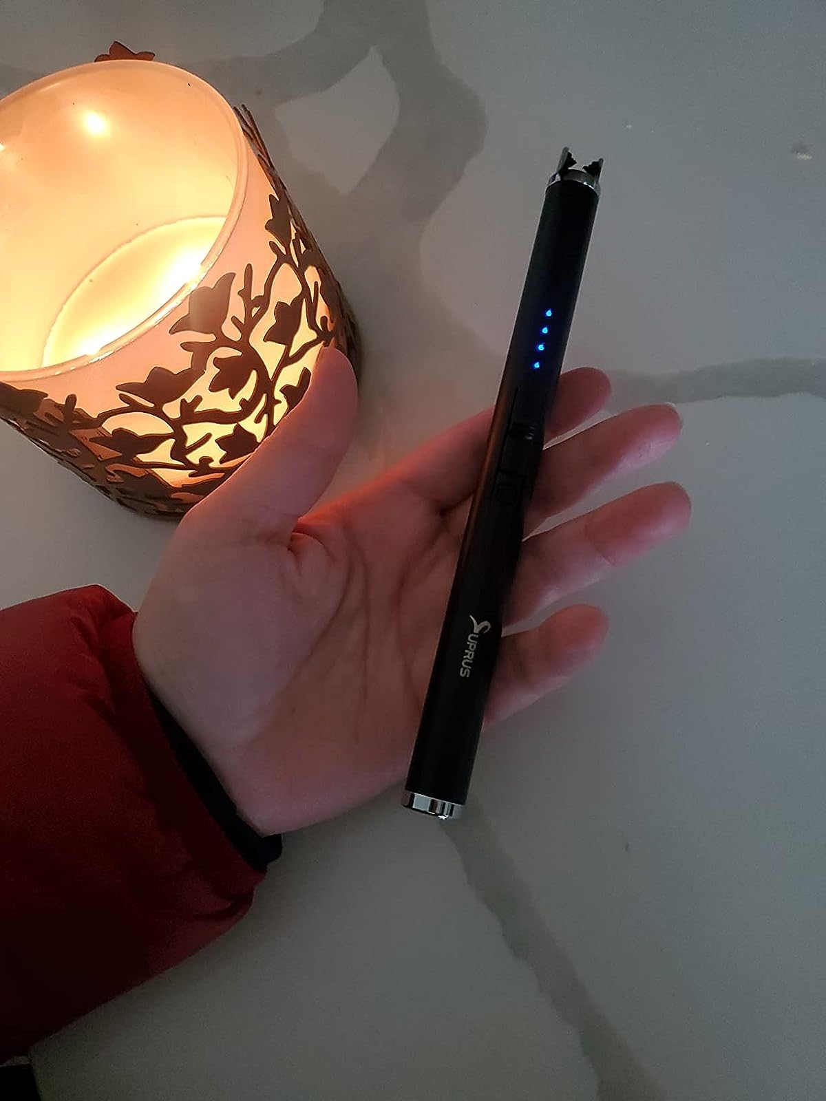 Reviewer holding the electric lighter next to a lit candle