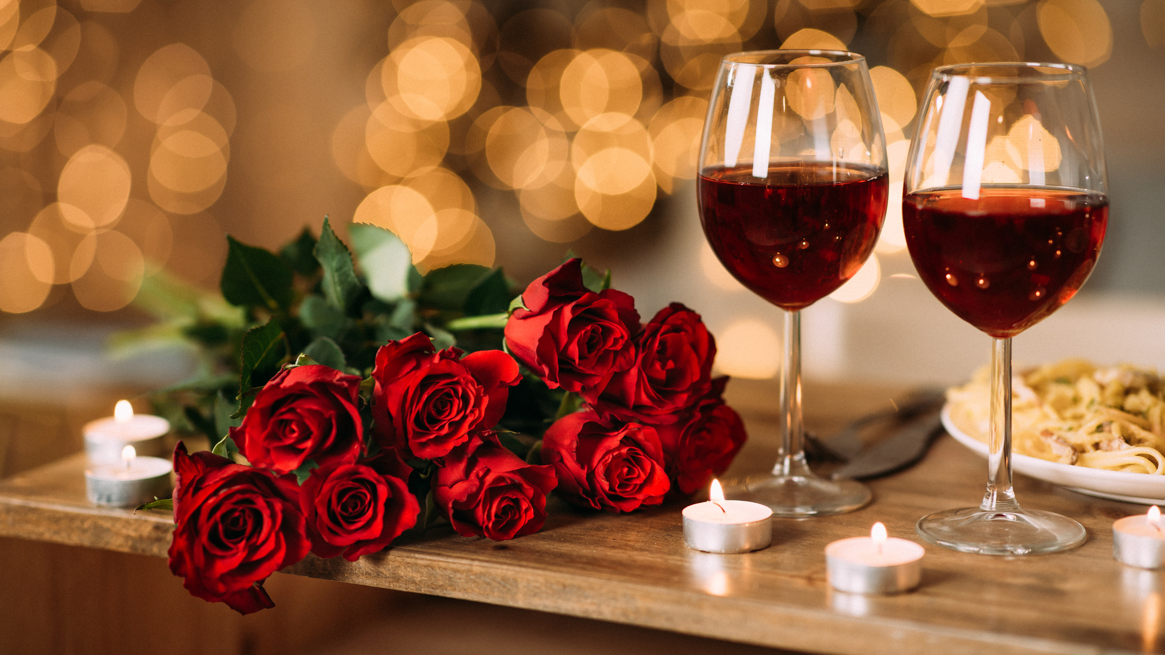 two wine glasses and roses on a table