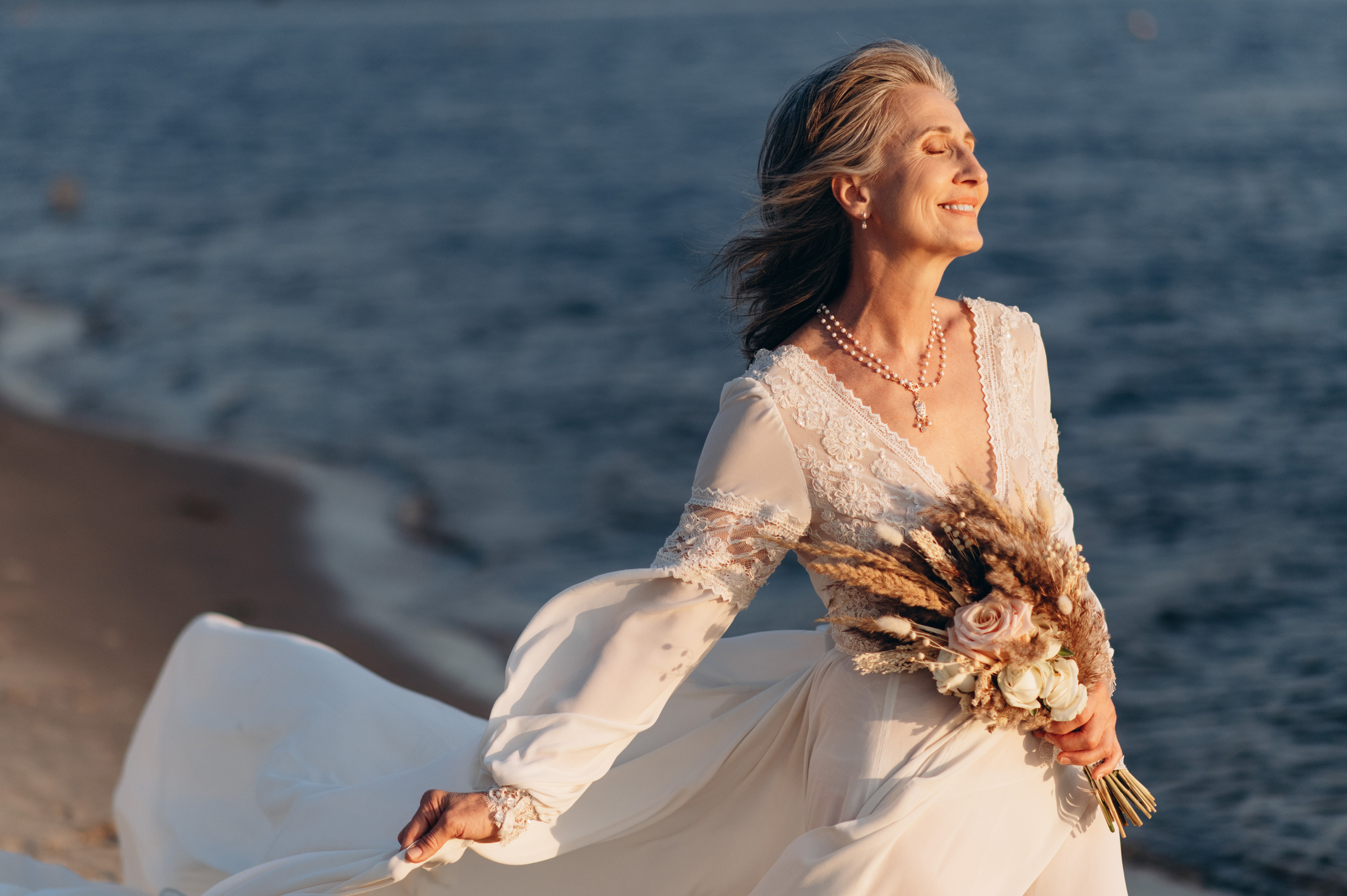 older woman in a wedding dress on the beach