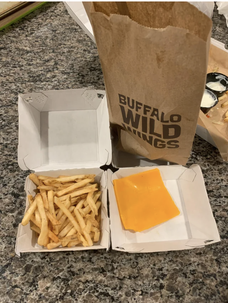 Fries and slices of unmelted American cheese on the side in a takeout container