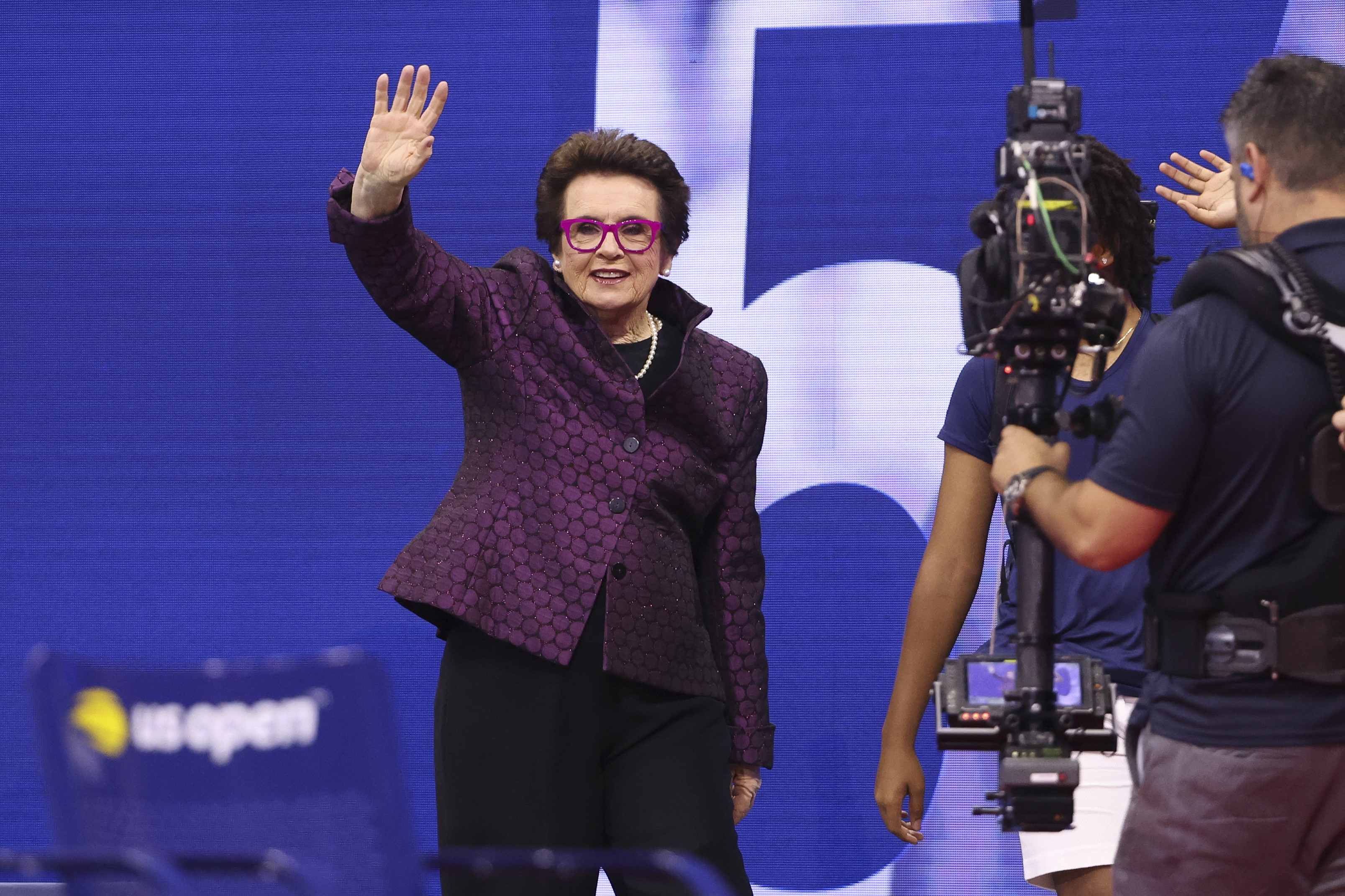 Billie Jean King waving to the crowd as she walks on court