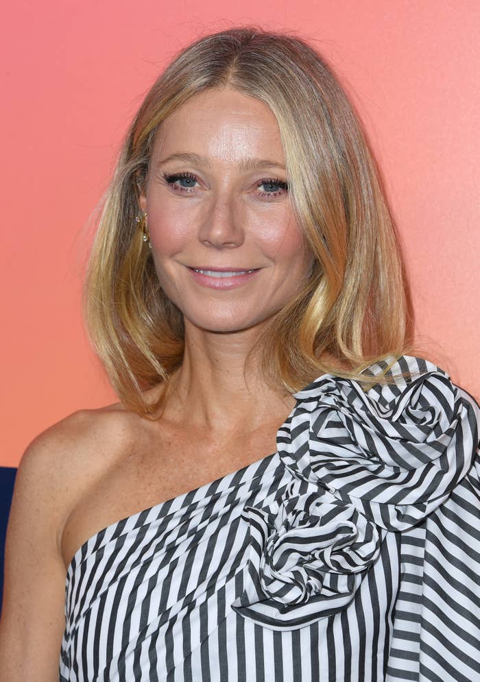 Close-up of Gwyneth smiling and wearing a one-shoulder striped outfit