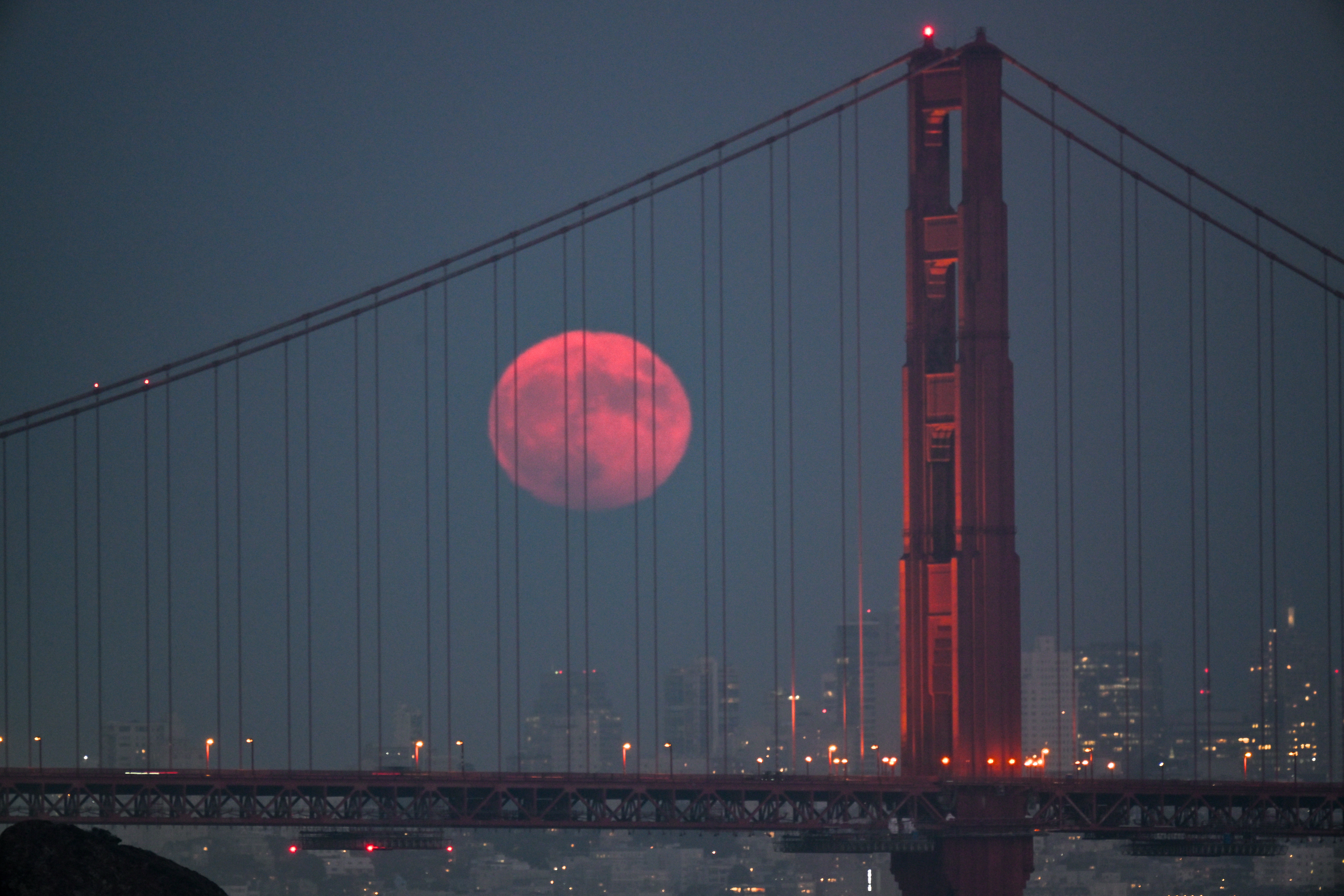 The blue supermoon is seen behind the Golden Gate Bridge in San Francisco